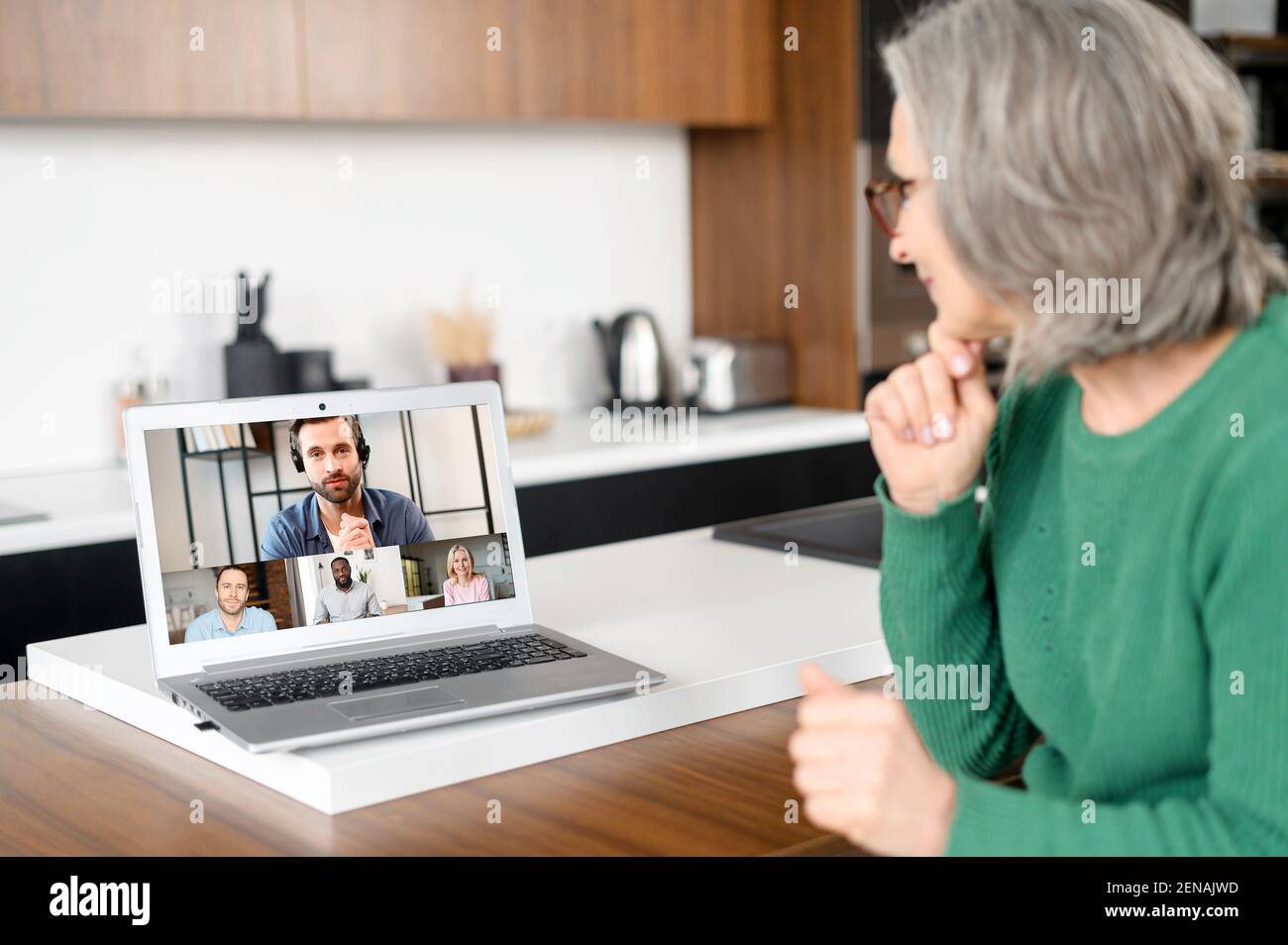 Lächelnder Unternehmer, alte Frau sitzt am Laptop, zu Hause, Treffen mit den Geschäftspartnern, um die Ergebnisse der Zusammenarbeit, in verschiedenen Teilen der Welt, Entfernung ist kein Hindernis Stockfoto