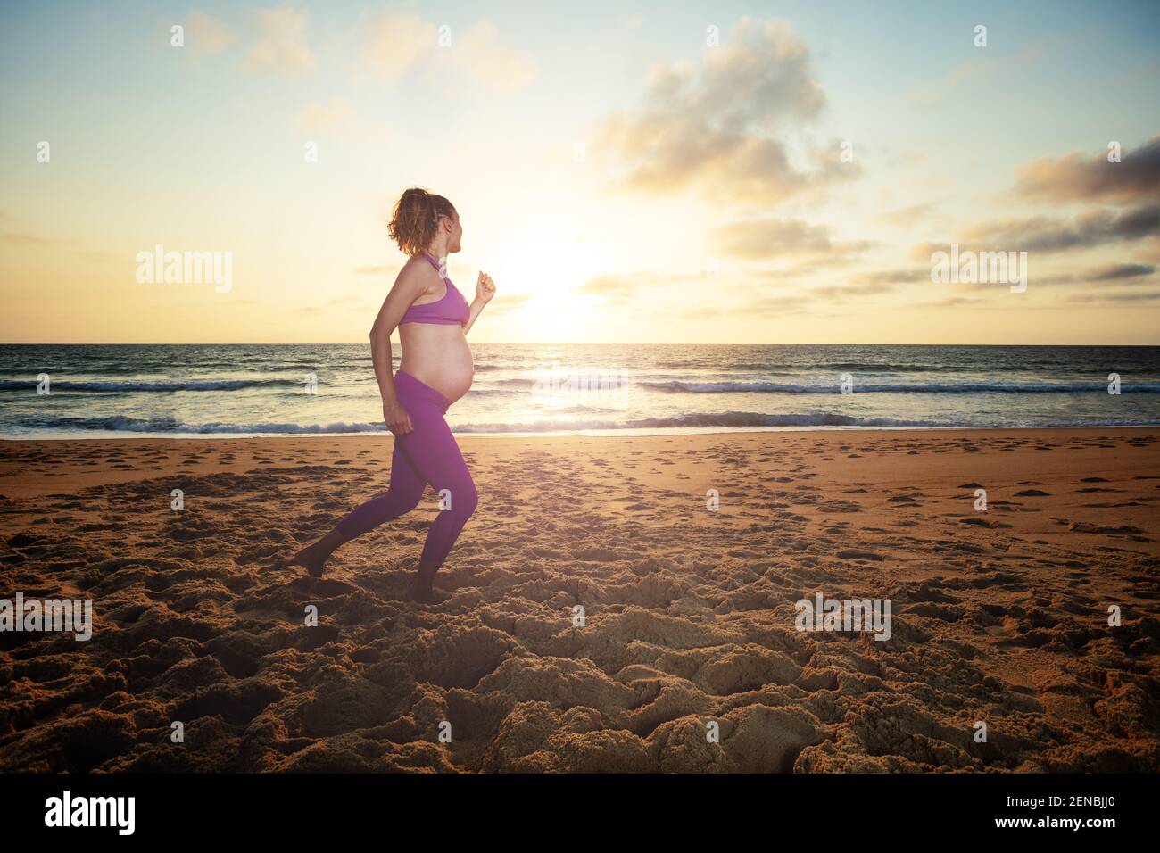 Schwangere Frau joggt am Strand über den Sonnenuntergang Stockfoto