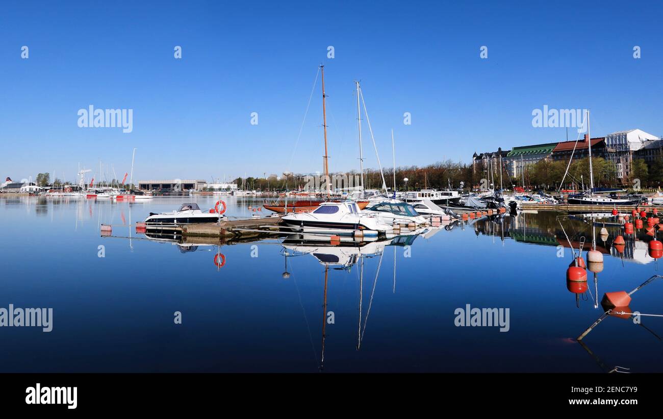 Blauer Himmel und blaues Meer mit Spiegelungen in einem Bootshafen an einem ruhigen Sommermorgen in Helsinki, Finnland. Stockfoto