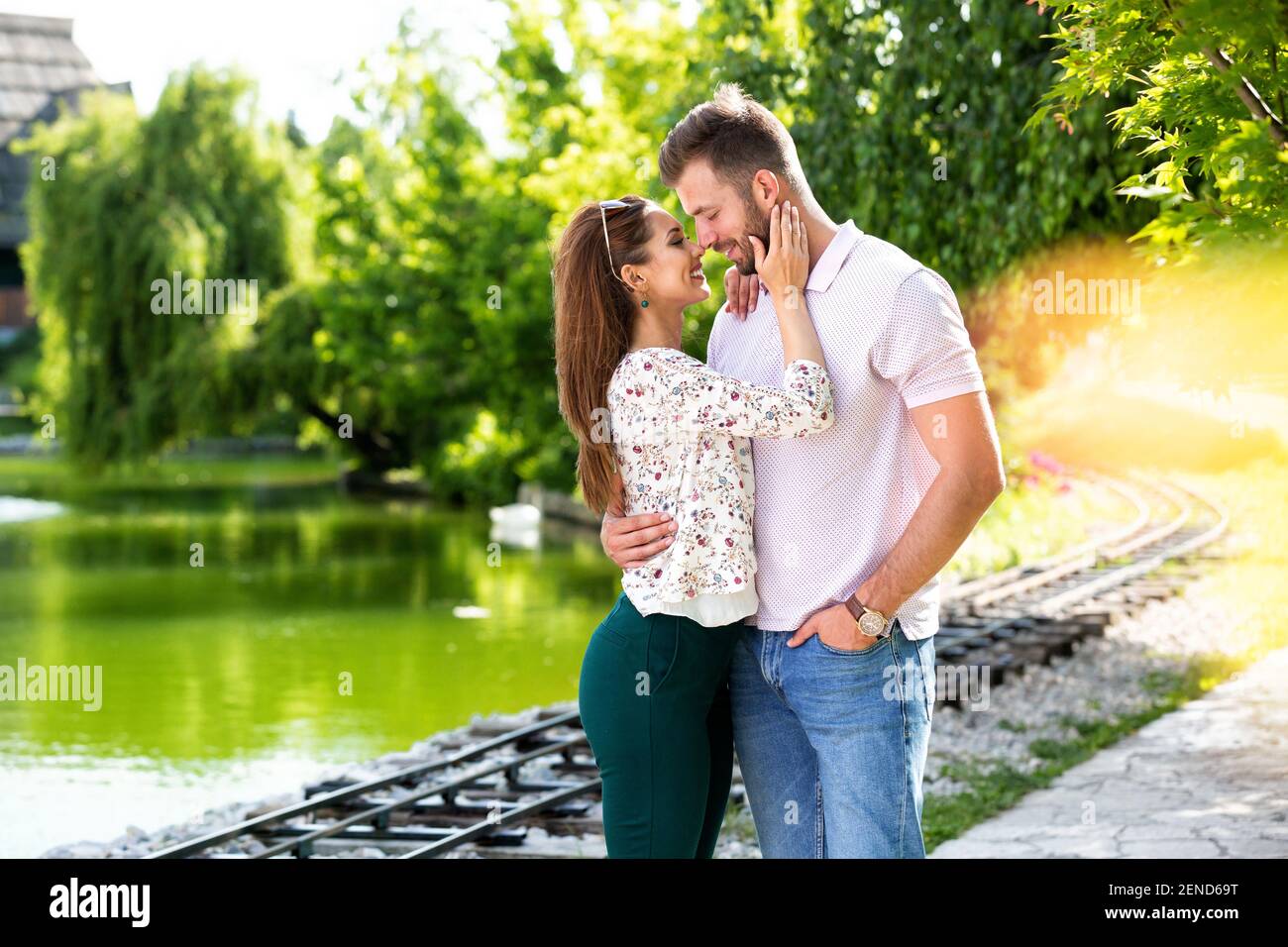 Romantisches Paar lächelt neben einem See und genießt jeden Moment Stockfoto