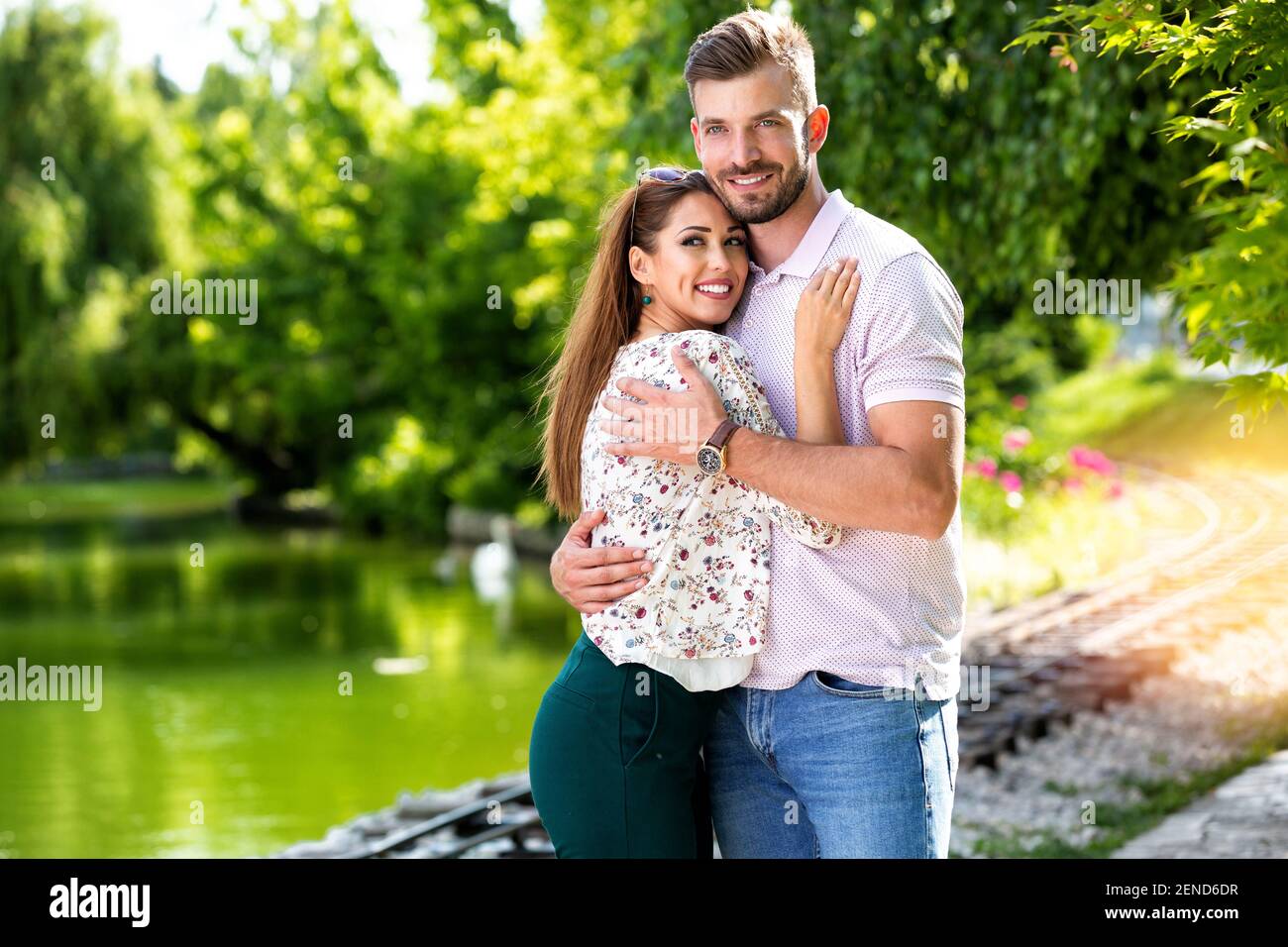 Romantisches Paar lächelt neben einem See und genießt jeden Moment Stockfoto