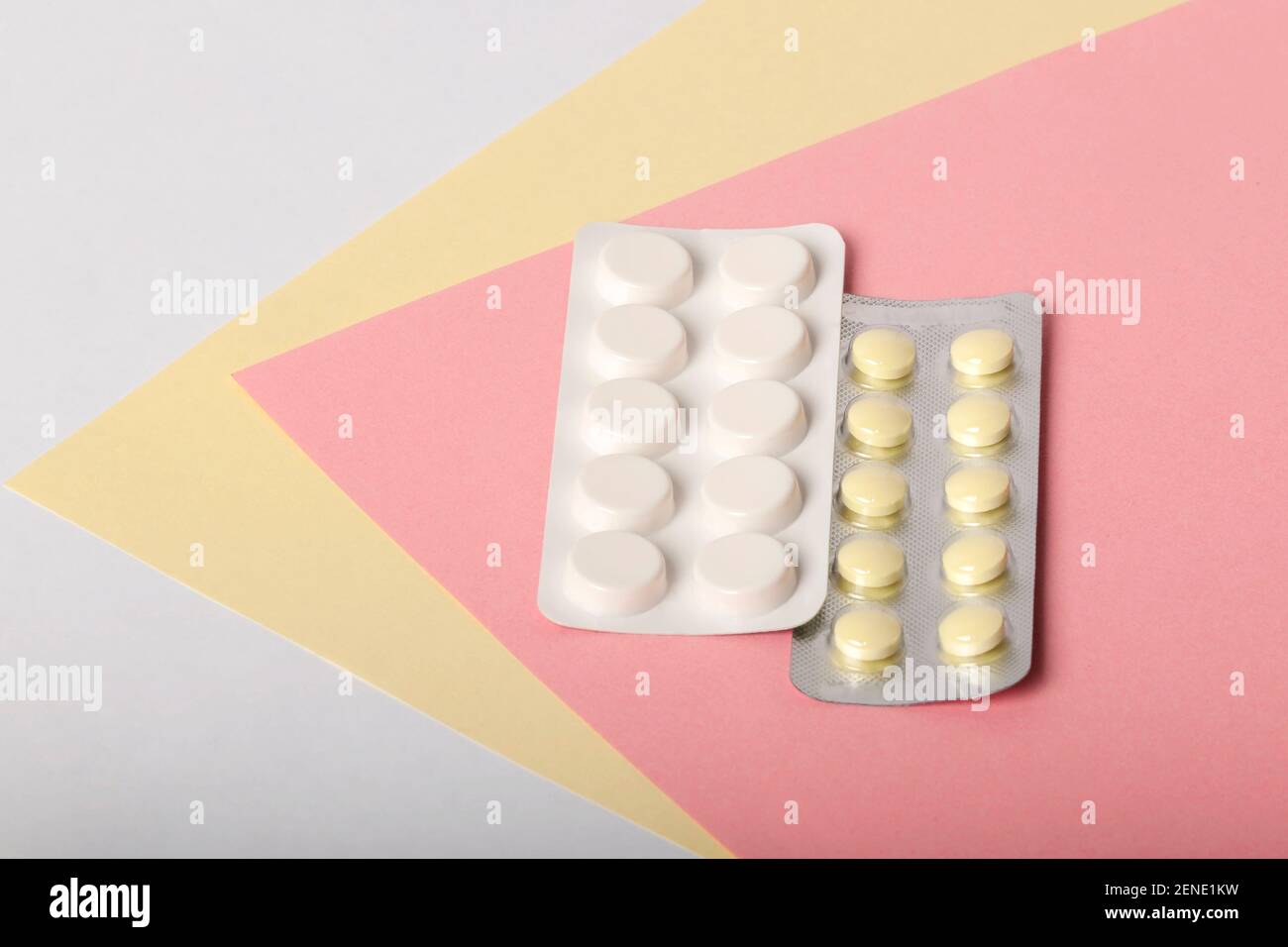 Weiße und gelbe Medikamente liegen auf einem mehrfarbigen Hintergrund Stockfoto