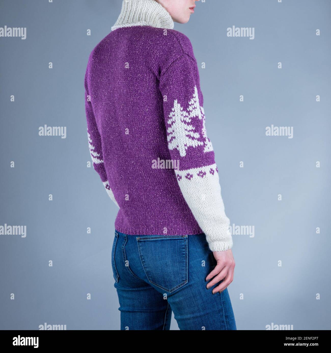 Nahaufnahme von Yang Frau in lila Pullover und blaue Jeans. Weihnachtlicher  Pullover. Grauer Hintergrund Stockfotografie - Alamy