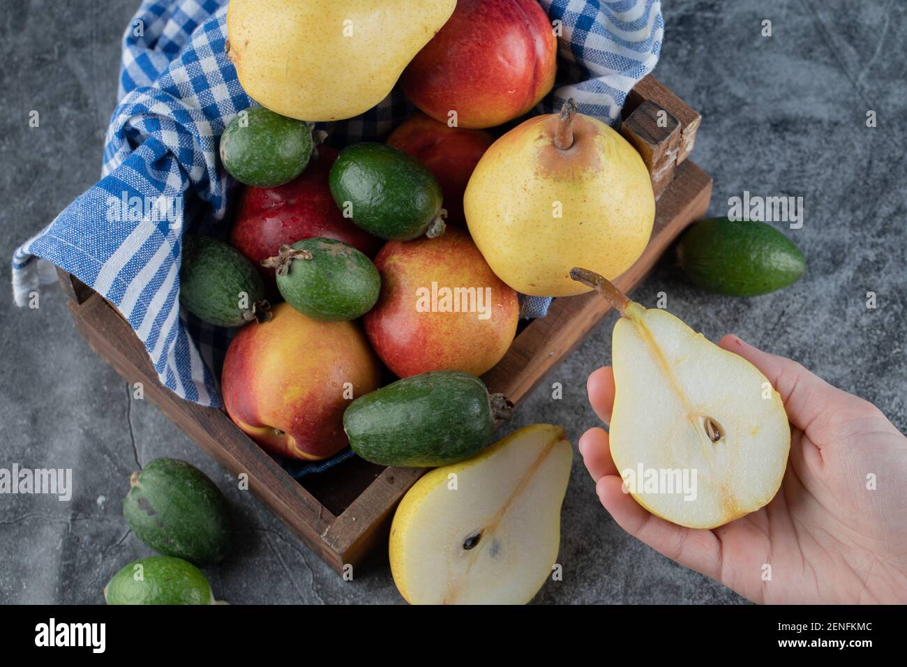 Blick von oben auf den Korb mit frischem Obst. Weibchen mit halbgeschnittener Birne Stockfoto