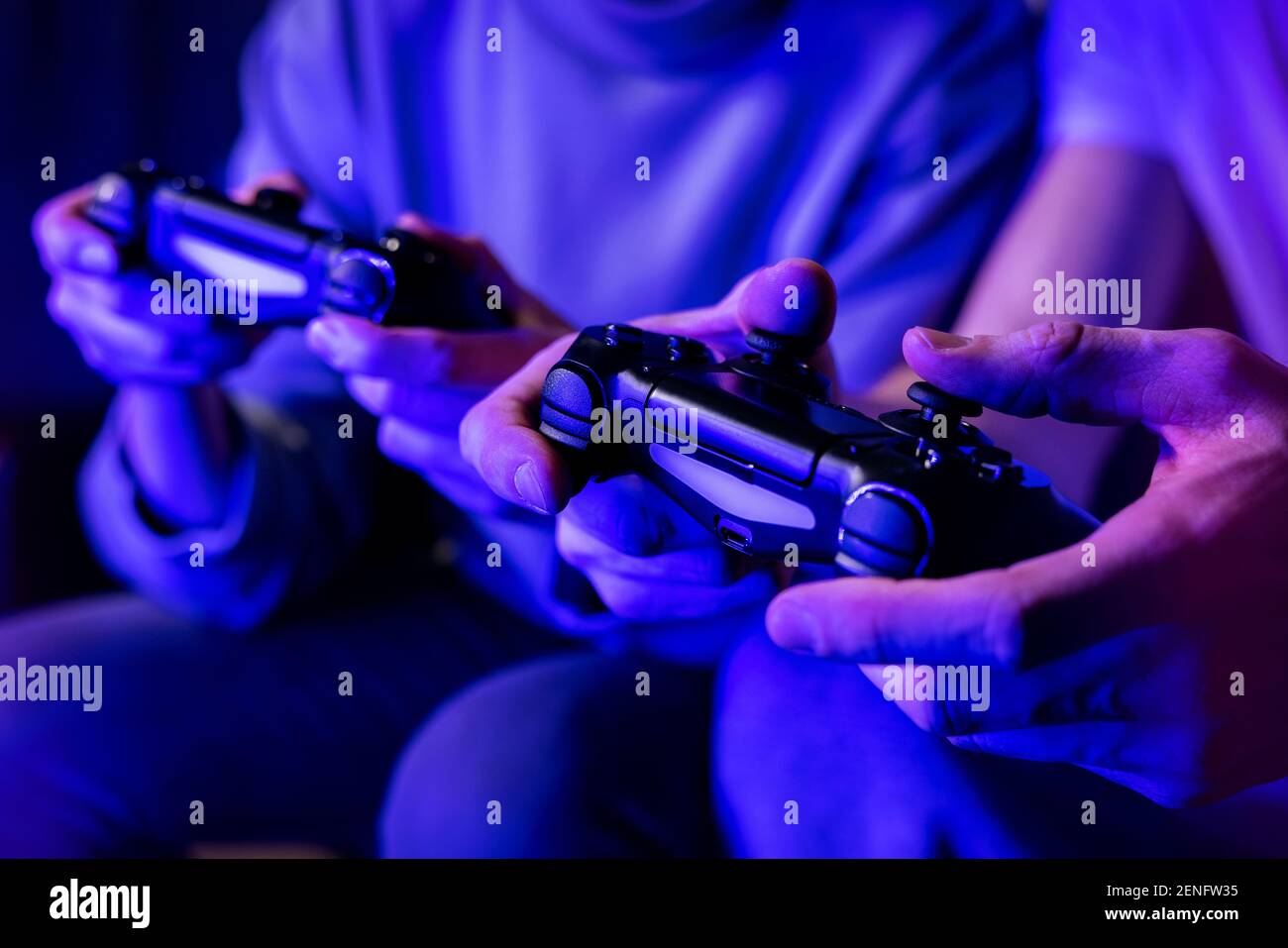 Freunde spielen Konsole Videospiele. Controller in Händen Nahaufnahme. Neon-Lichter Stockfoto