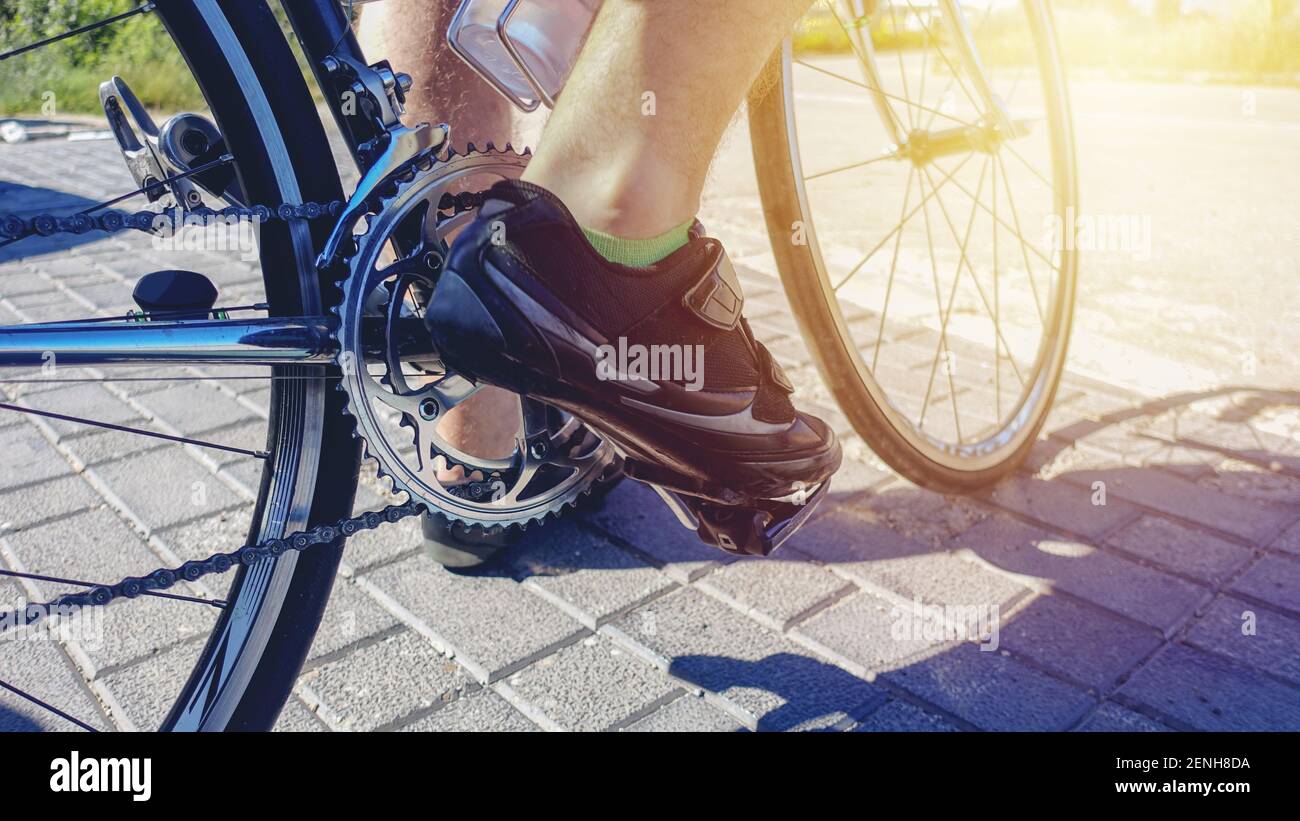 Radler Fuß auf einem professionellen Sportfahrrad. Nahaufnahme der Fahrradkette. Detail der Fahrrad-Metall-Komponenten - Kette, hintere Kassette, Umwerfer, b Stockfoto