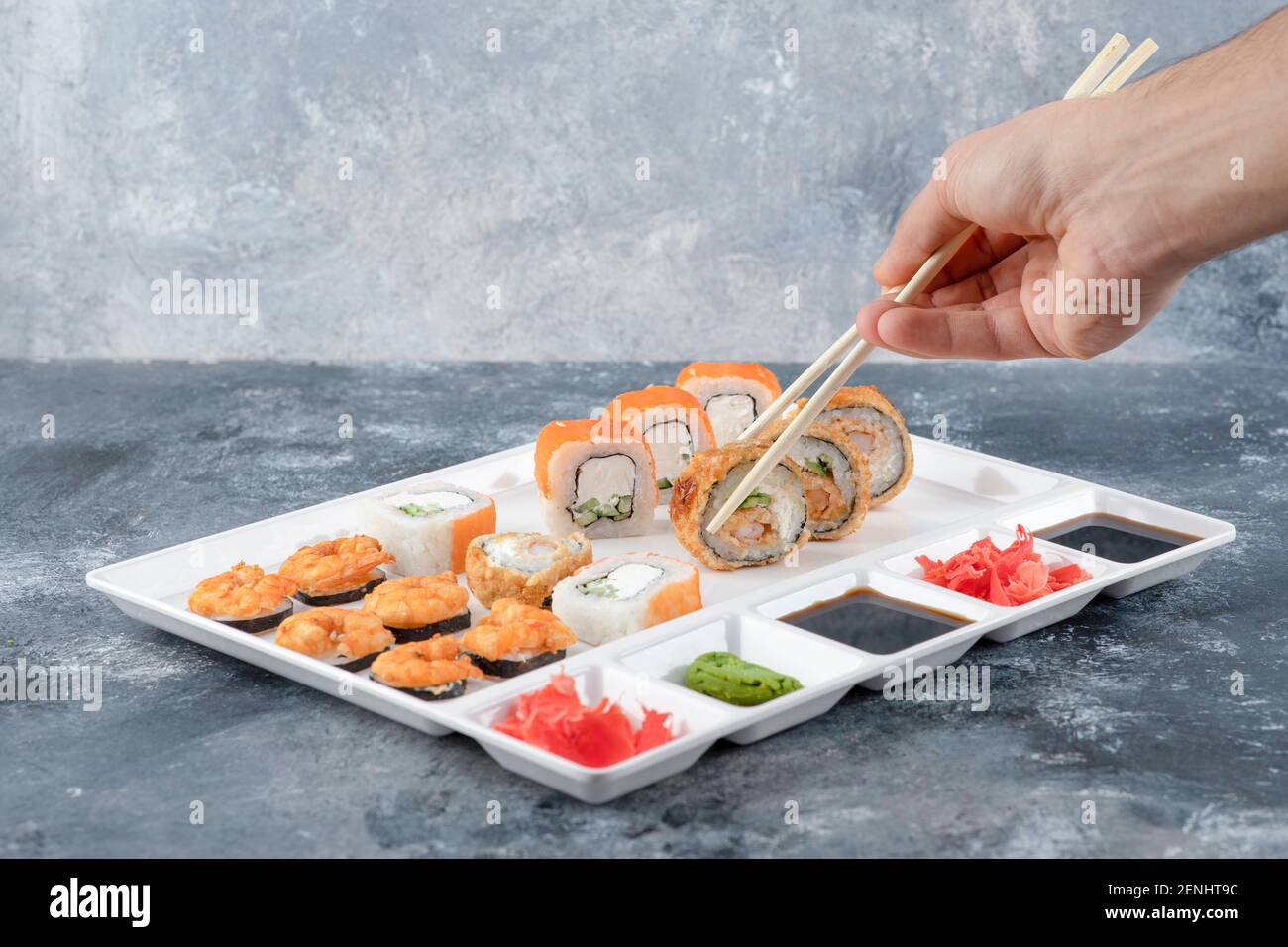 Mann Hand nehmen panierte heiße Sushi-Rolle mit Essstäbchen Stockfoto