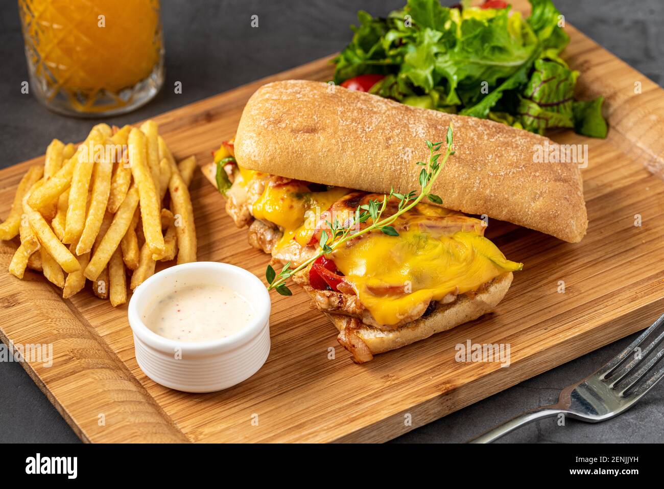 Gegrilltes Hähnchen- und Cheddar-Sandwich mit pommes Frites und Salat. Stockfoto