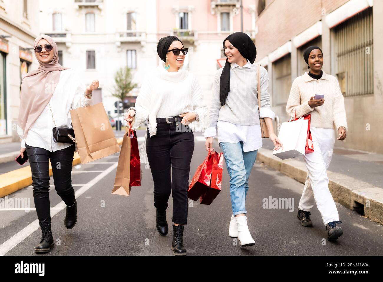 Vier Freundinnen, die mit der Straße entlang gehen Stockfoto