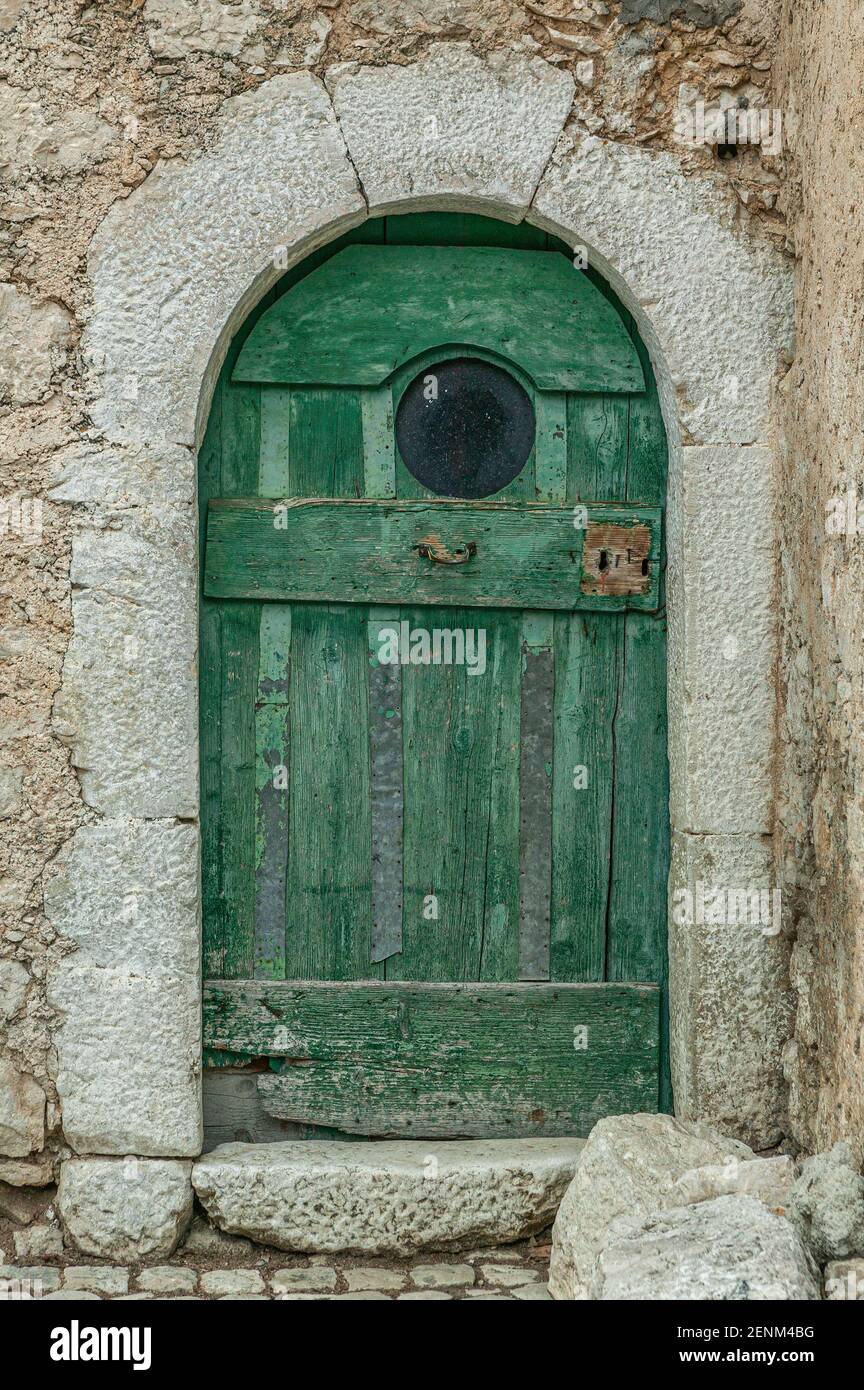Grüne Tür in einem Steinhaus mit einem runden Bullauge. Abruzzen, Italien, Europa Stockfoto