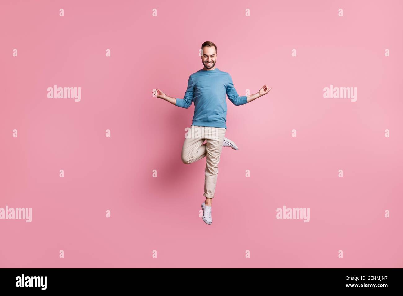 In voller Länge Foto von friedlichen charmanten jungen Kerl tragen blau pullover springen ein Bein genießen Yoga isoliert rosa Hintergrund Stockfoto