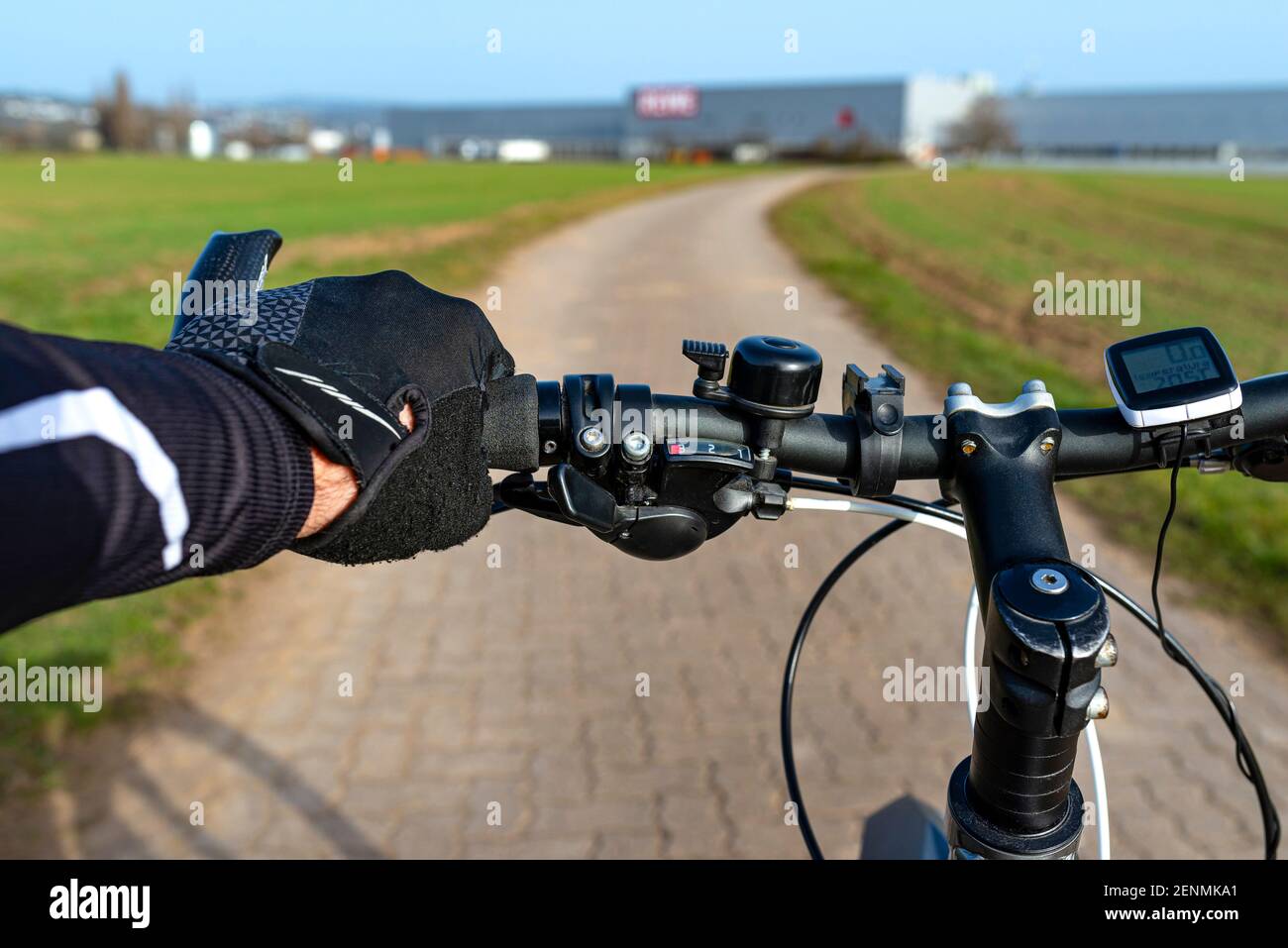 Ein Fahrradlenker aus der Perspektive der ersten Person und mit einer mans Hand am Griff. Sichtbarer Fahrradcomputer und Glocke. Stockfoto