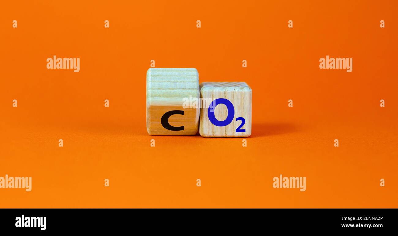 Symbol CO2 oder O2. Drehte den Holzwürfel und änderte die Worte 'CO2, Kohlendioxid' in 'O2, Sauerstoff'. Schöner orangefarbener Hintergrund, Kopierbereich. Geschäftlich, e Stockfoto