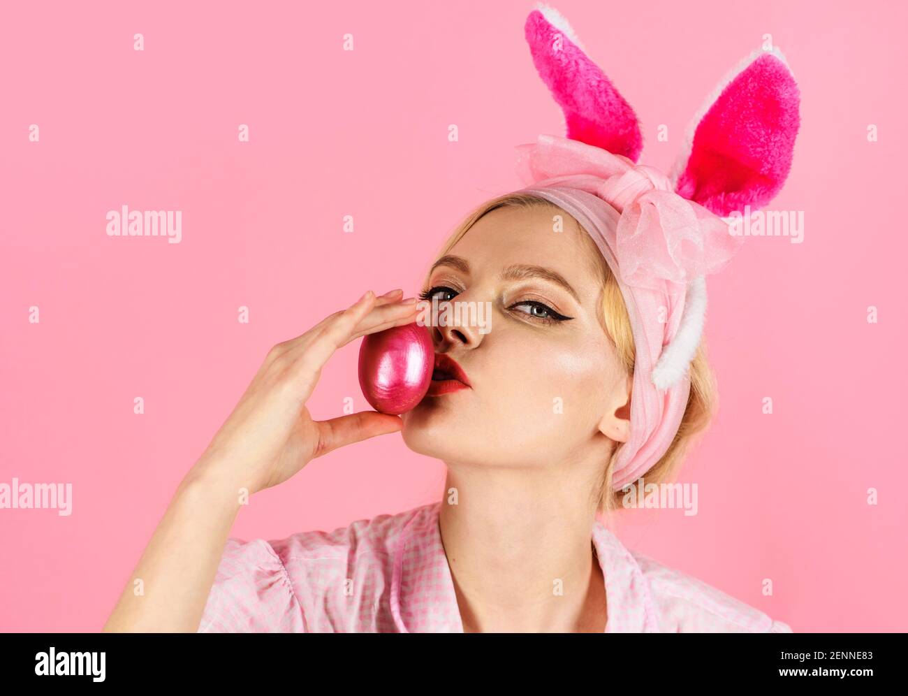 Eier jagen. Frau mit Hasenohren küssen Osterei. Frühlingsurlaub. Lustige Kaninchen Mädchen. Stockfoto