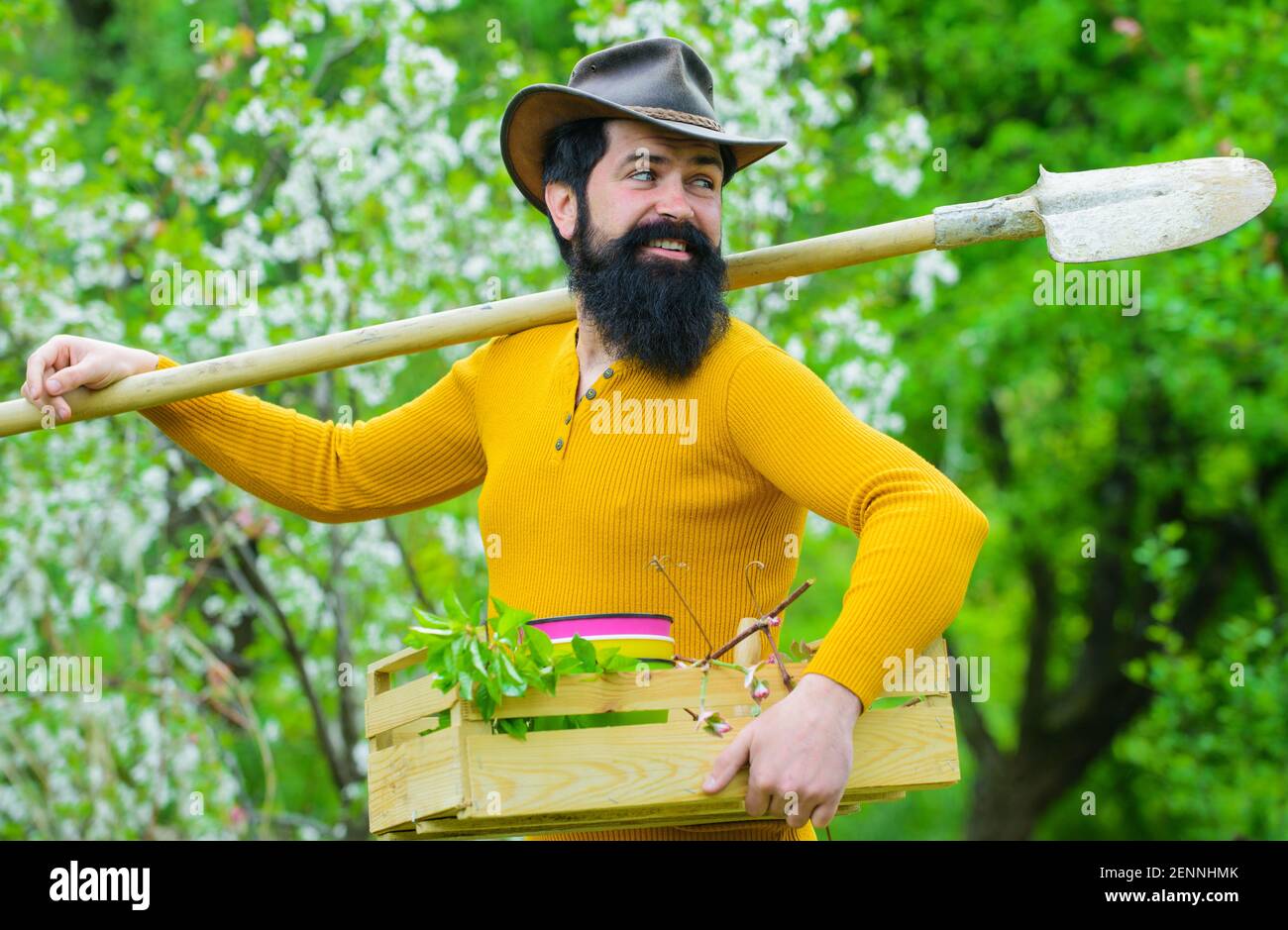 Landwirt im Frühlingsgarten. Glücklicher Gärtner mit Spaten. Bärtiger Mann mit Gartengeräten. Stockfoto