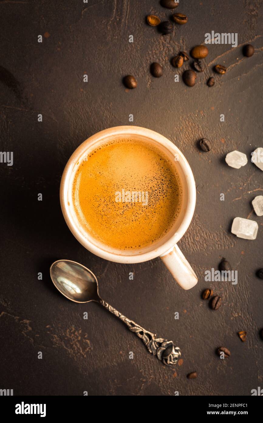 Tasse Kaffee mit Kaffeebohnen auf braunem Hintergrund. Stockfoto