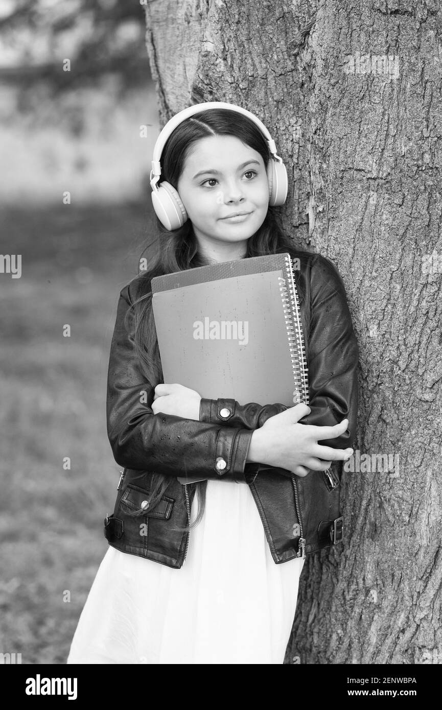 Mädchen hören Audio tragen Lehrbücher entspannende Park Hintergrund, Bibliothek Playlist Konzept. Stockfoto