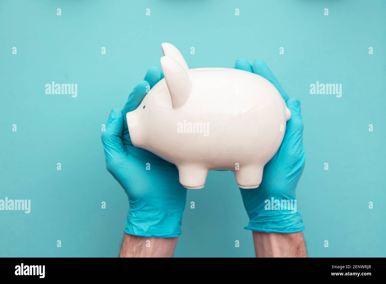 Gesundheitskosten. Arzt in chirurgischen Handschuhen mit einem weißen Sparschwein Stockfoto