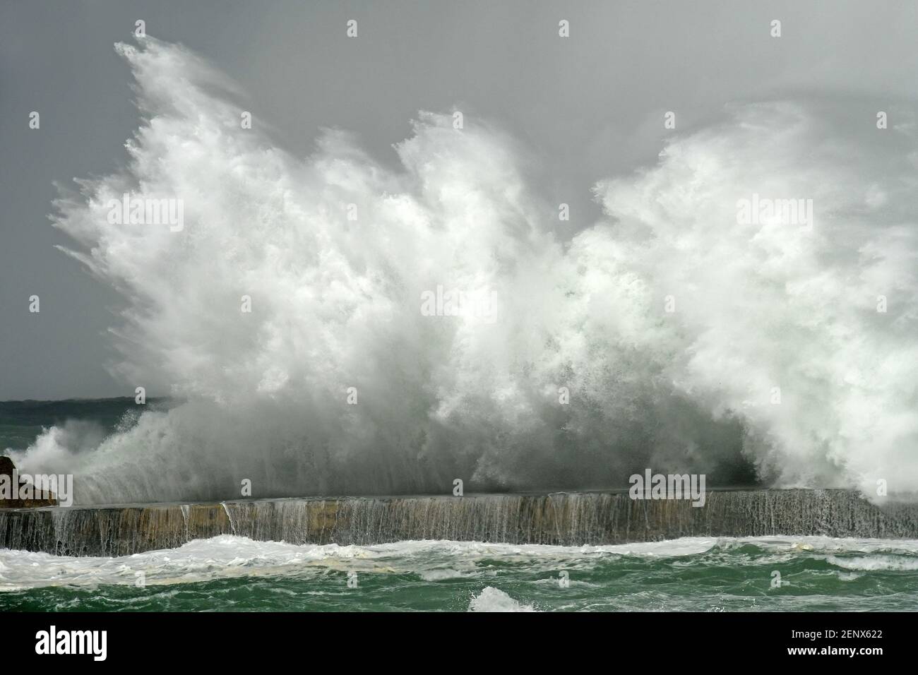 Wellenbruch an der Steinmauer in einem stürmischen Wintertag Stockfoto