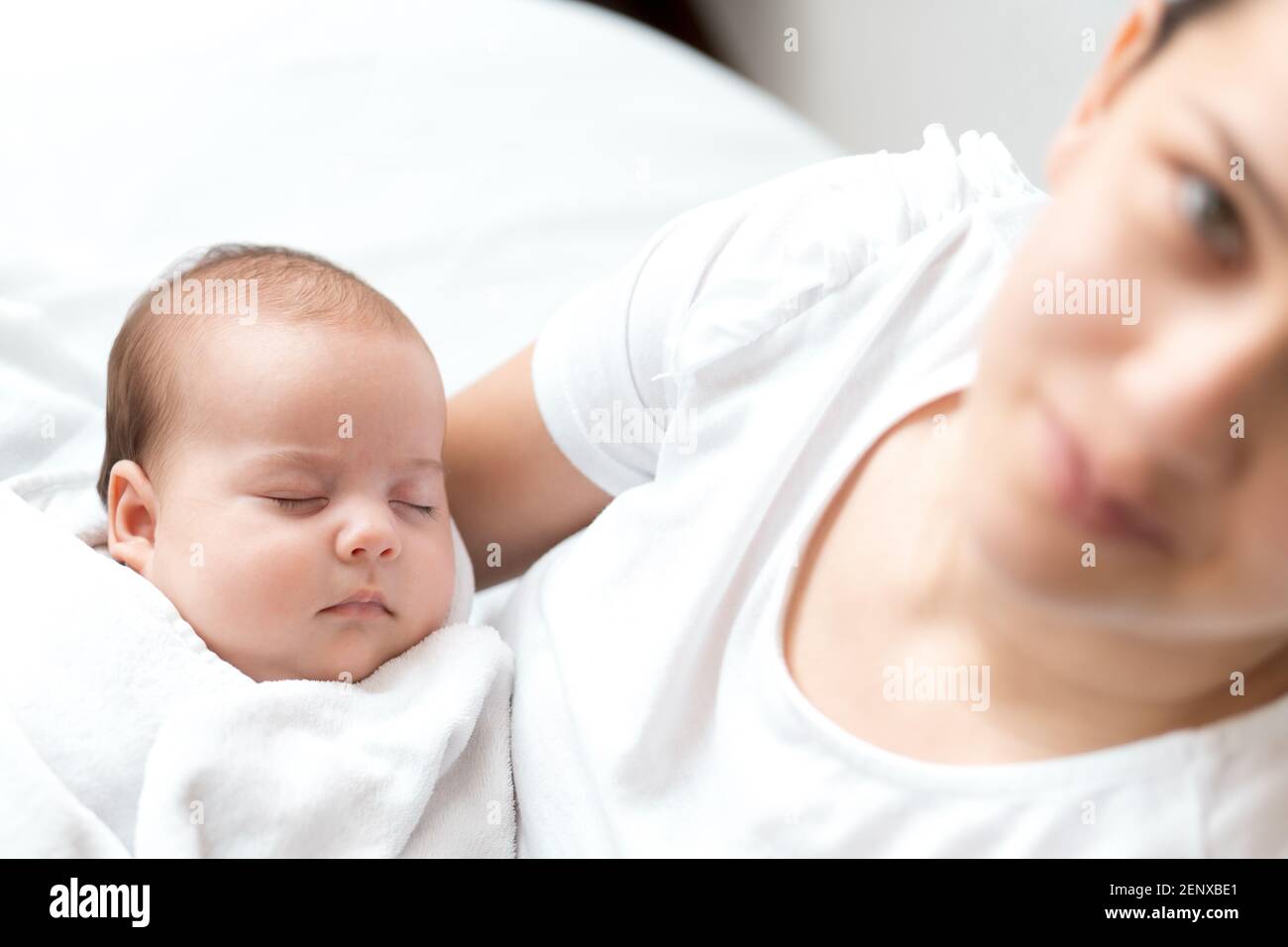 Nahaufnahme Porträt von Mutter mit neugeborenem Baby auf weißem Hintergrund Kopie Raum. Junge nette kaukasische Frau schwarz behaart halten Kind in den Armen Mutterschaft Stockfoto
