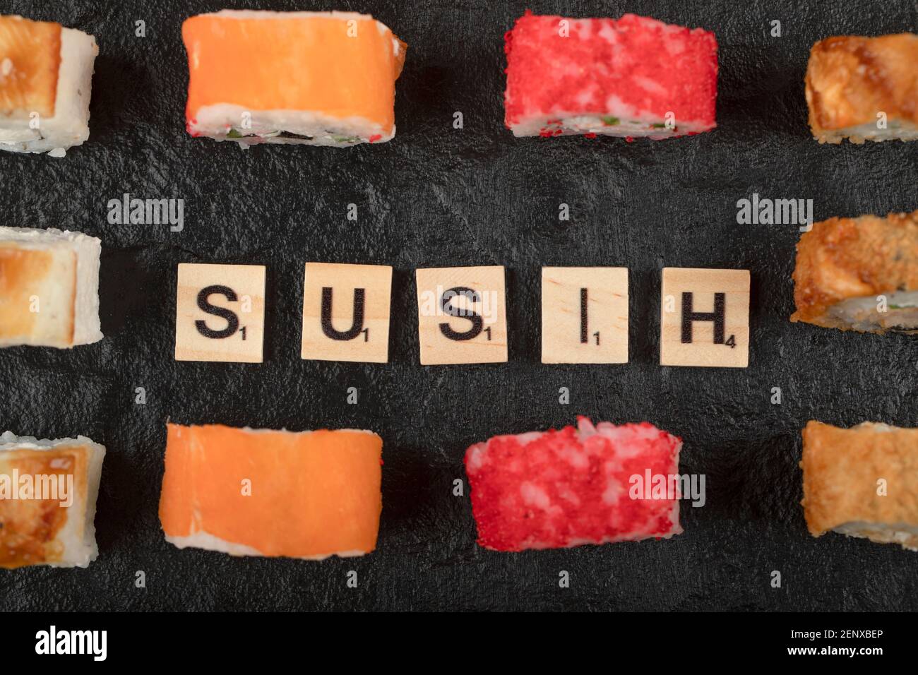 Set von Sushi-Rollen mit Holzbuchstaben geschrieben als Sushi Auf schwarzer Oberfläche Stockfoto