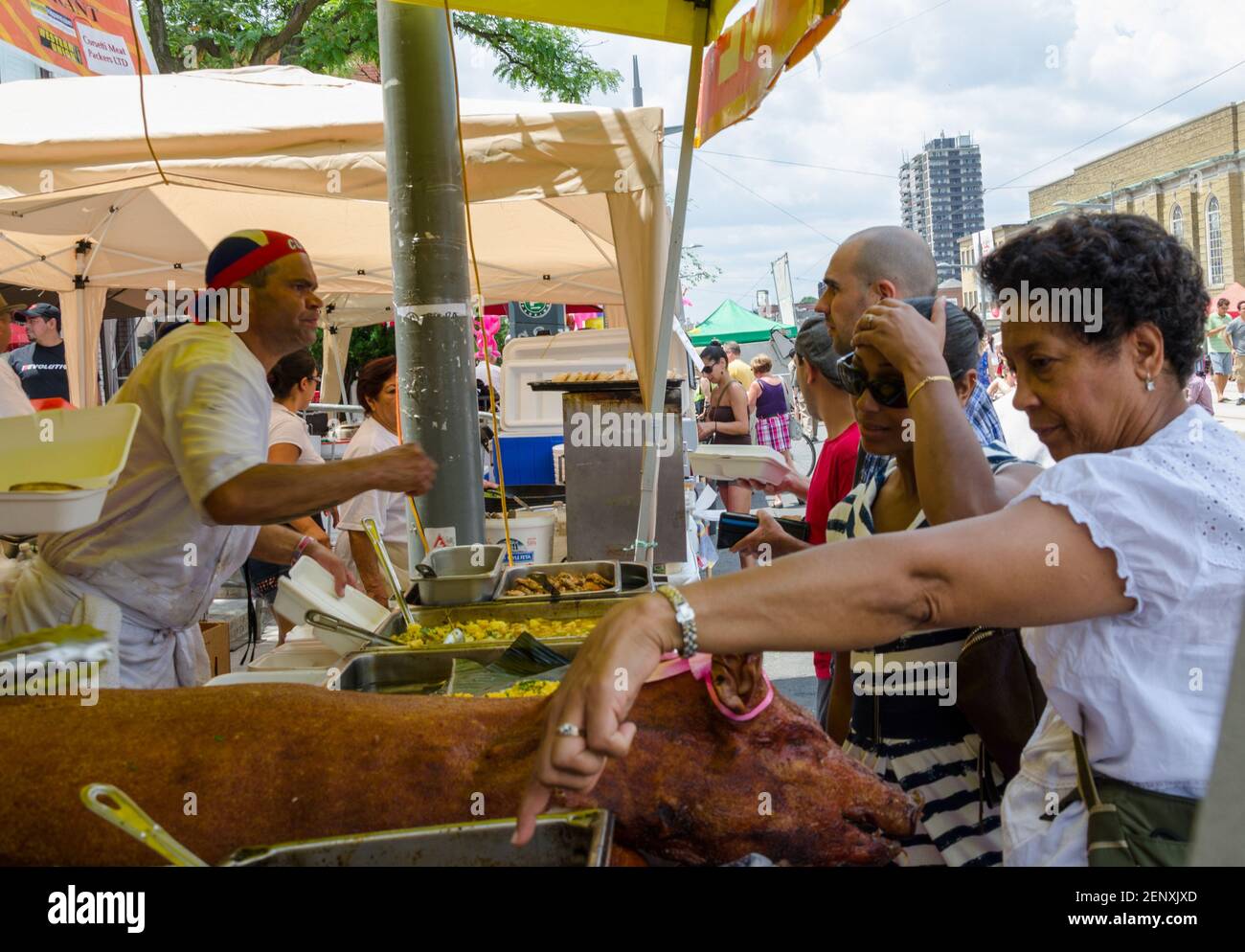 Salsa auf dem St. Saint Clair Festival Szenen: Die Leute an einem Outdoor-Food-Stand schauen über die Serviertabletts, um zu entscheiden, was sie essen wollen. Die Dame im Stockfoto