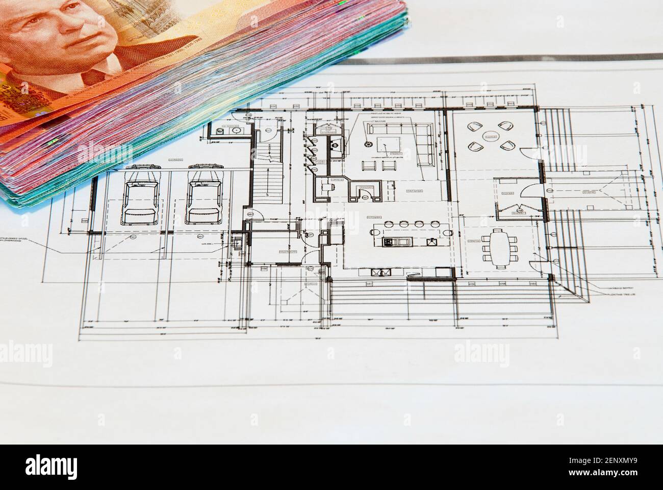 Finanzierung eines Bauprojekts. Haus-Design auf weißem Papier mit einem Haufen Geld am Rande Stockfoto