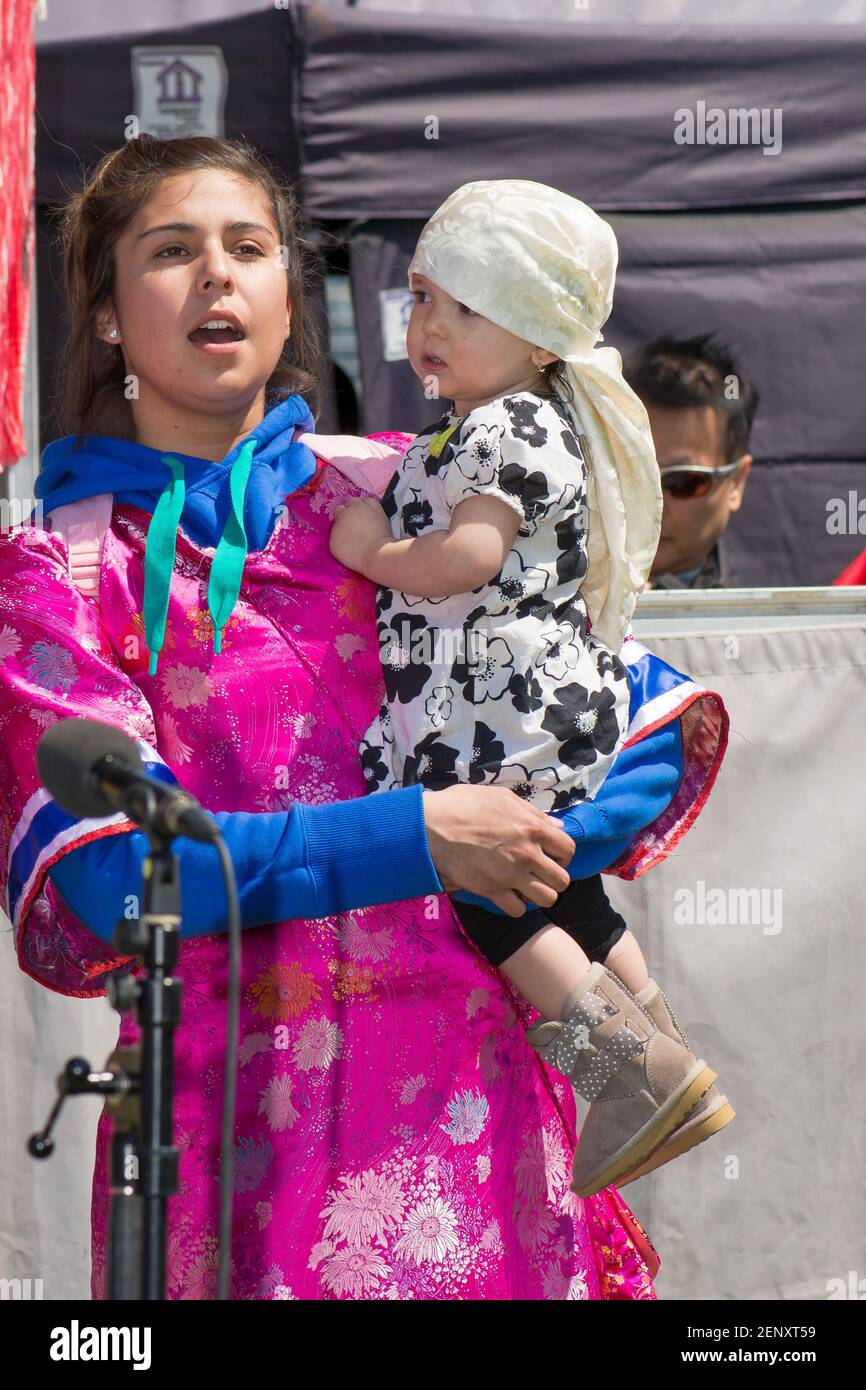 Kanadische First Nation Frau mit Kind: Ethnische Indianer Frau mit Baby auf Händen singen in traditionellen Kostümen. Die Zeremonie findet als Toronto ce statt Stockfoto