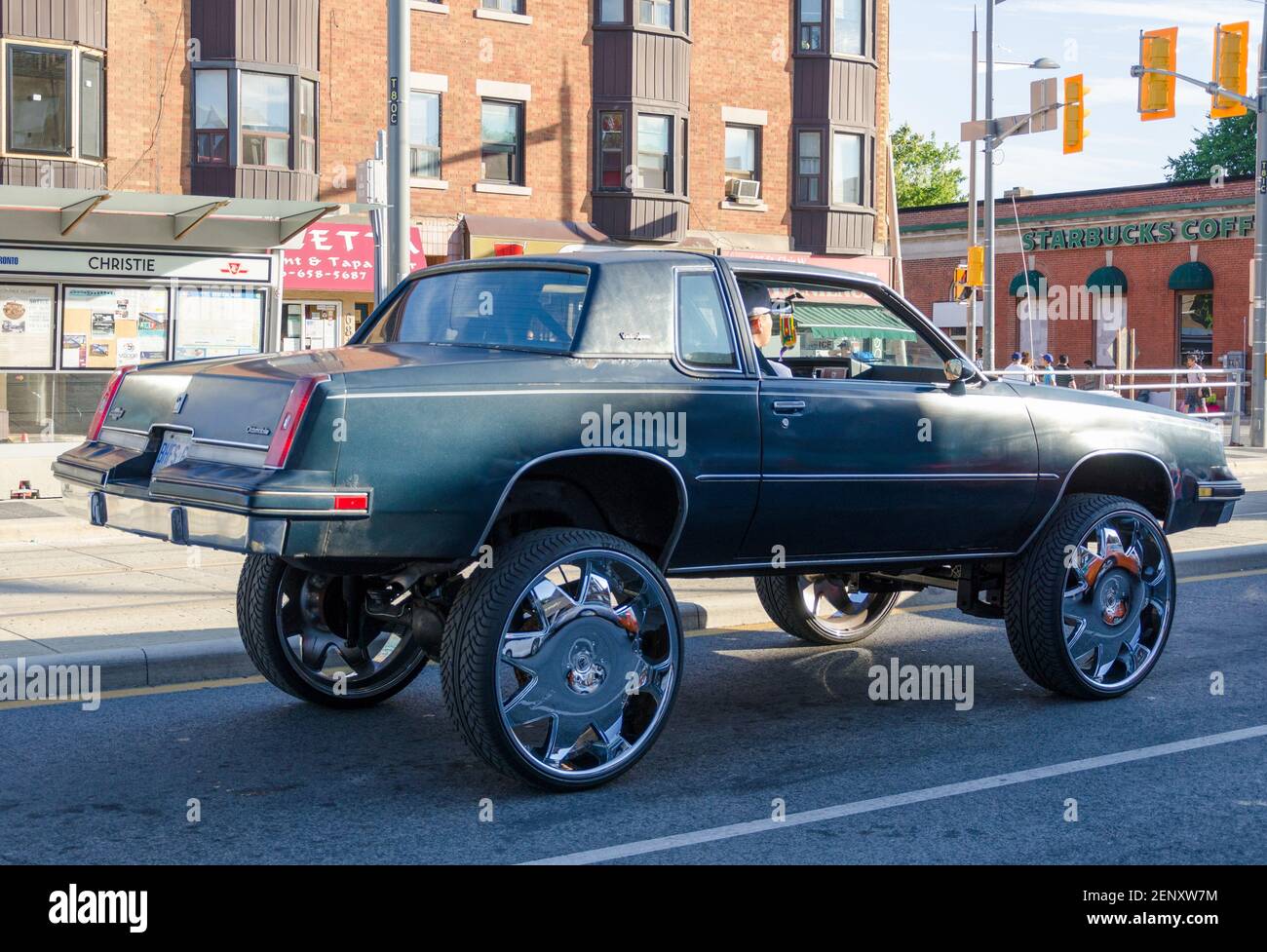 Eine benutzerdefinierte dunkelgraue Hot Rod wartet auf die Ampel zu ändern, wie es eine Fahrt in die Innenstadt dauert. Das Oldtimer-Fahrzeug wurde durch Add aufgesoupt Stockfoto Eine benutzerdefinierte dunkelgraue Hot Rod wartet auf die Ampel zu ändern, wie es eine Fahrt in die Innenstadt dauert. Das Oldtimer-Fahrzeug wurde durch Add aufgesoupt Stockfoto