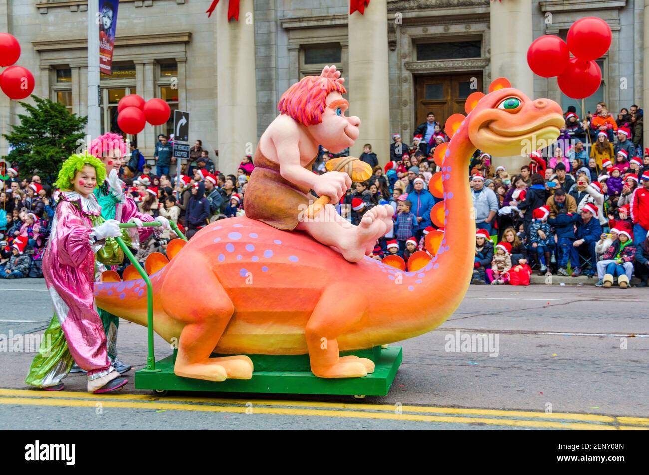 Caveman auf einem Dinosaurier-Mini-Floß bei der Feier der Ausgabe 109th der Santa Claus Parade. Mehr als eine halbe Million Menschen besuchen das PAR Stockfoto