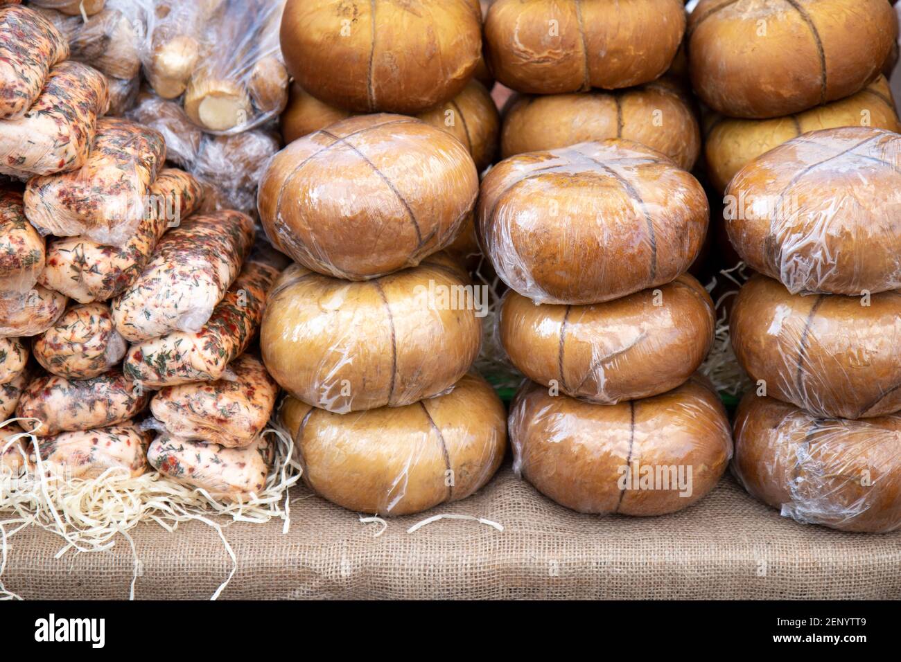 Verschiedene geräucherte Adyghe Käse in Packungen und in der Masse auf Marktzähler Stockfoto