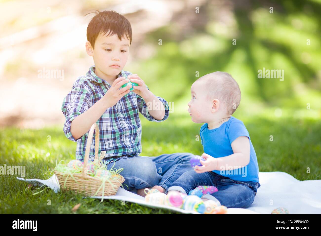 Gemischte Rasse chinesische und kaukasische Jungen draußen im Park spielen mit Ostereiern. Stockfoto