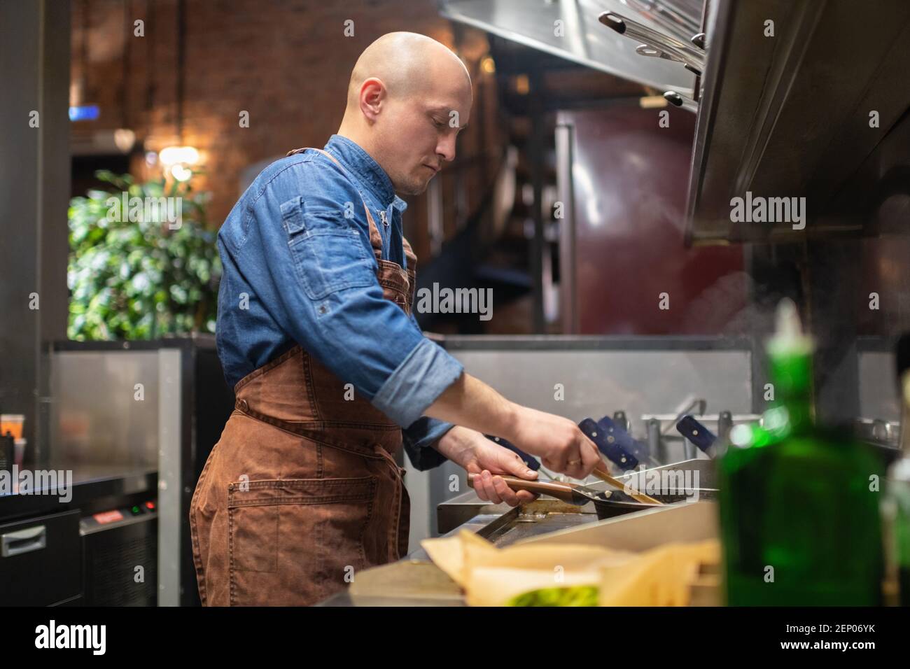 Glatze Rühren heiße Speisen auf Pfanne während der Zubereitung Essen in der Cafeküche Stockfoto