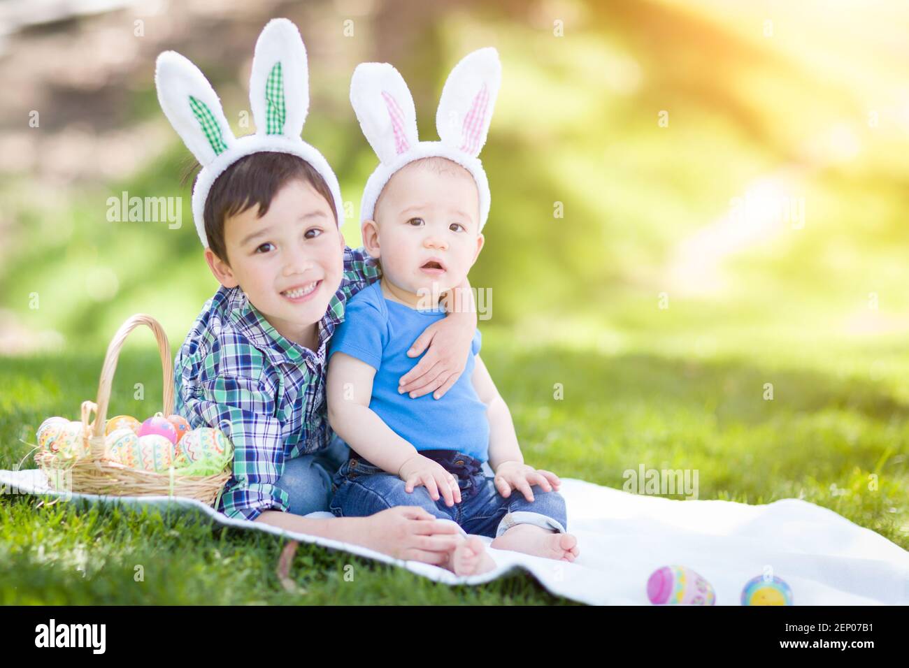 Gemischte Rasse chinesische und kaukasische Jungen draußen im Park spielen mit Ostereiern. Stockfoto