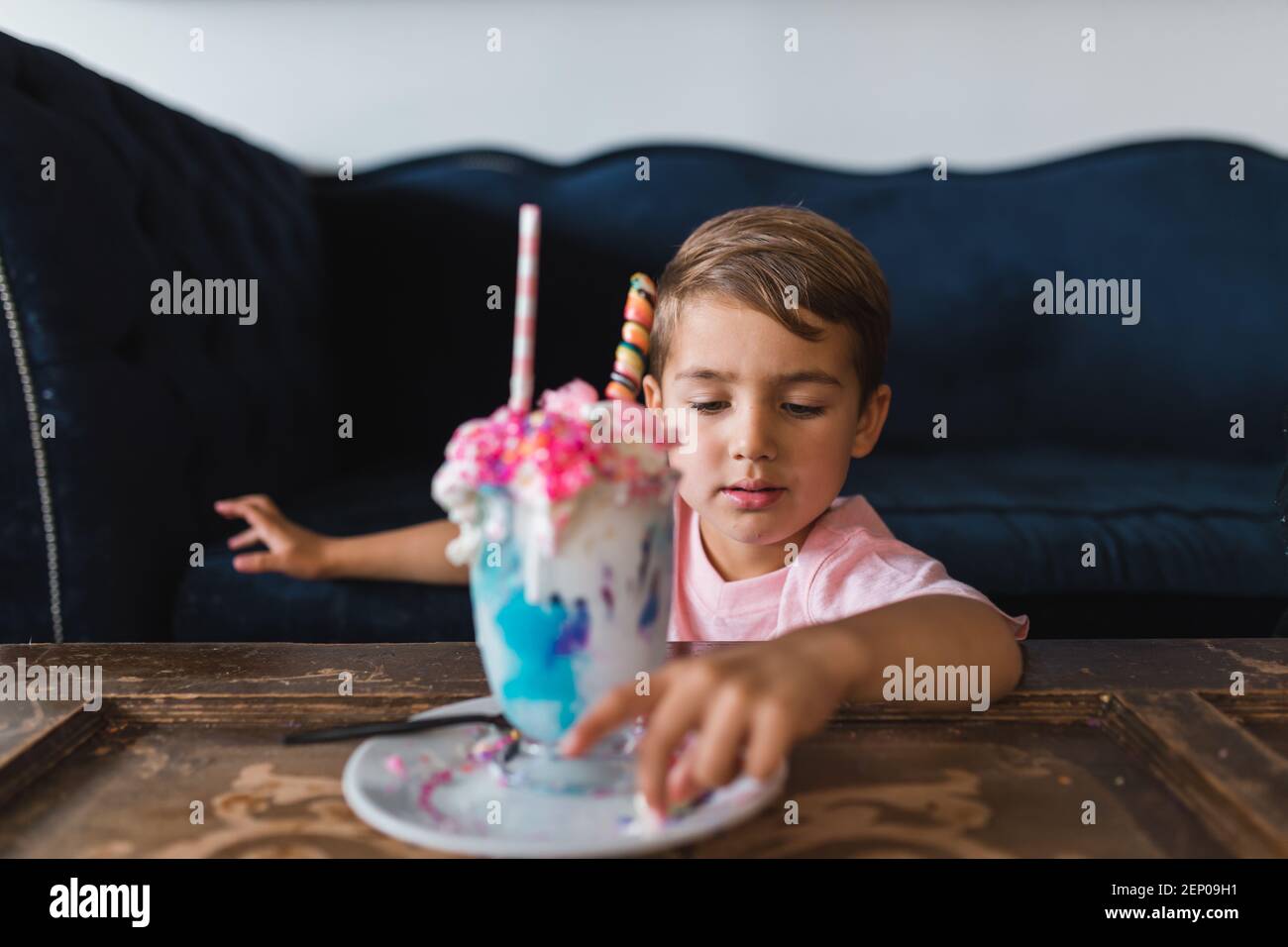 Kleiner Junge, der die Süßigkeiten von einem bunten Milchshake isst. Stockfoto