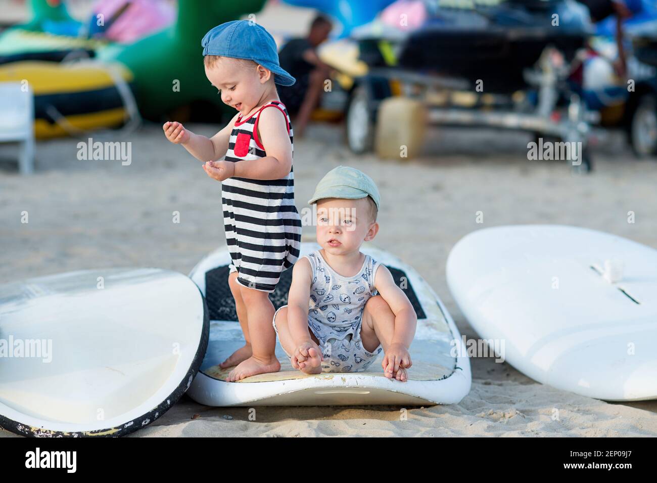 Zwillingsbrüder im Sommer Outfit spielen auf einem Brett in Windsurfing Camp Stockfoto