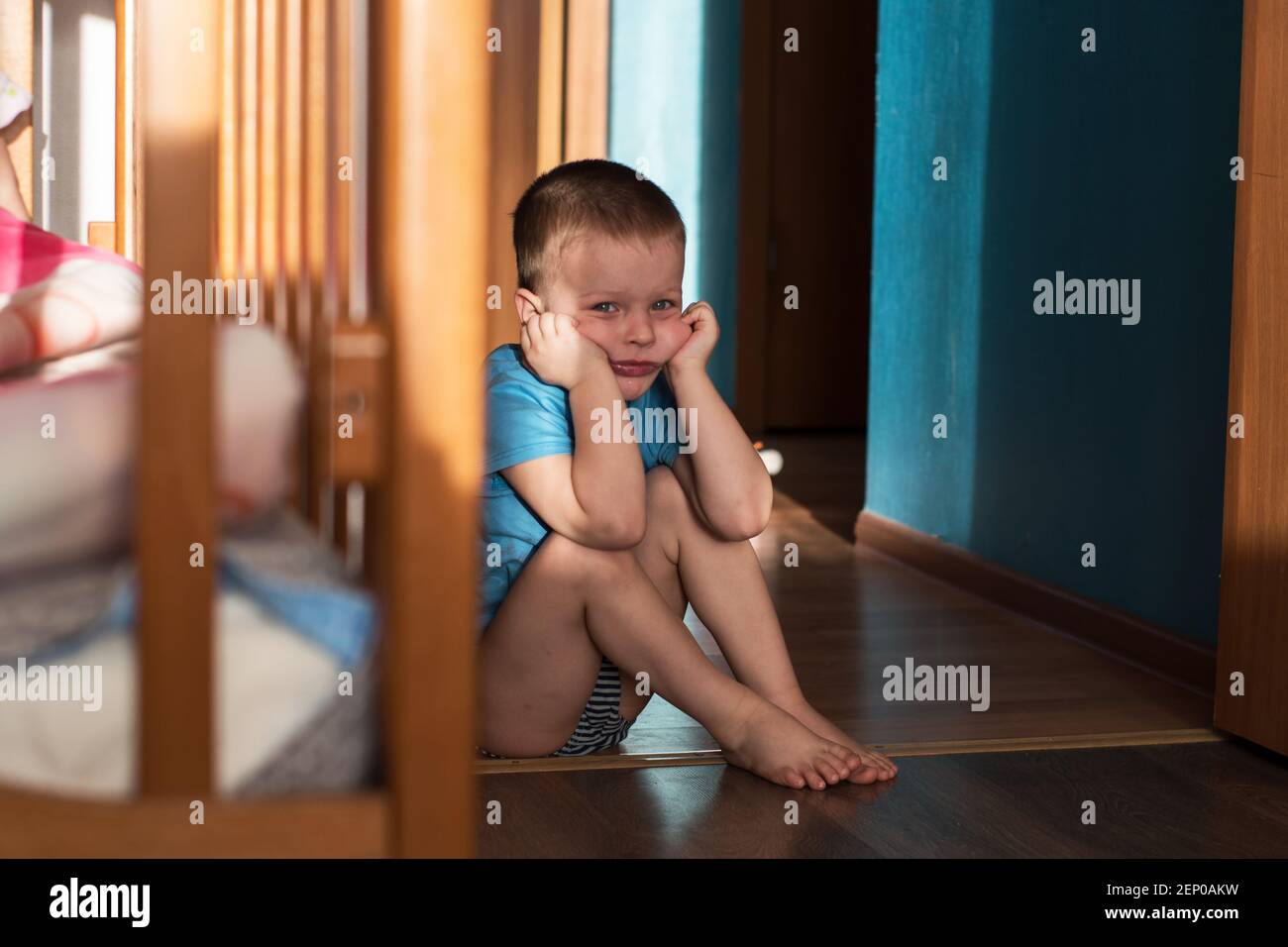 Ein kleiner Junge sitzt traurig auf dem Boden Ein Zimmer Stockfoto