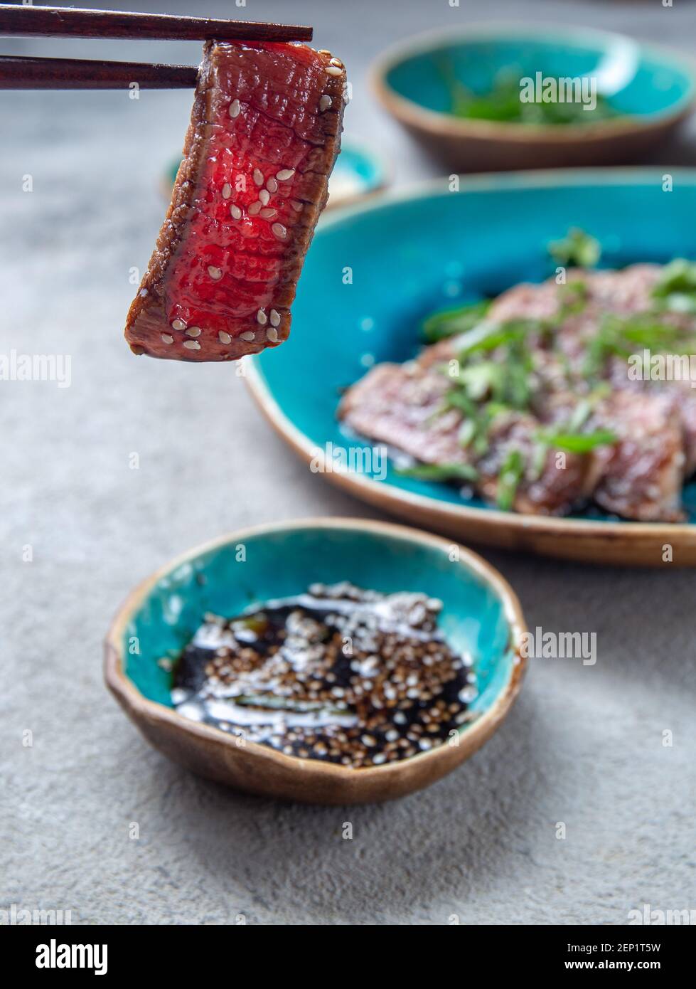 Rindertataki mit Sauce und Sesam auf blauem Teller. Japanisches Essen Stockfoto