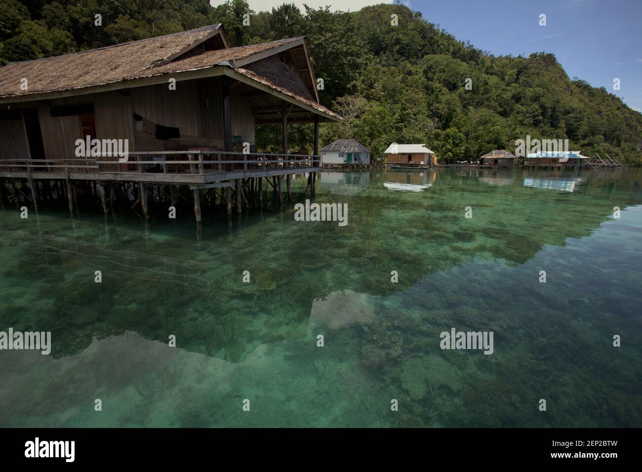 Pfahlbauten, die als Öko-Lodges über dem Küstenwasser in Sawai entworfen wurden, einem Fischerdorf, das sich teilweise verwandelt und Ökotourismus in Nord-Seram, Central Maluku, Maluku, Indonesien anbietet. Stockfoto