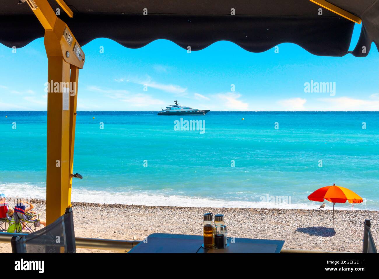 Eine Yacht fährt vor dem Plage de Casino an der Mittelmeerküste von Menton, Frankreich, an der französischen Riviera vorbei. Stockfoto