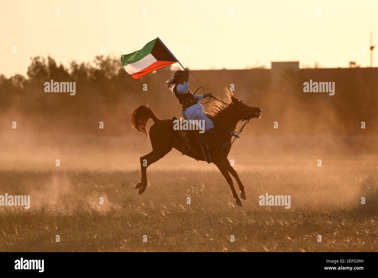 Peking, Kuwait. Februar 2021, 25th. Ein Mann, der eine kuwaitische Nationalflagge trägt, reitet ein Pferd während einer Reitausstellung in Mubarak Al-Kabeer Governorate, Kuwait, 25. Februar 2021. Kredit: Ghazy Qaffaf/Xinhua/Alamy Live Nachrichten Stockfoto