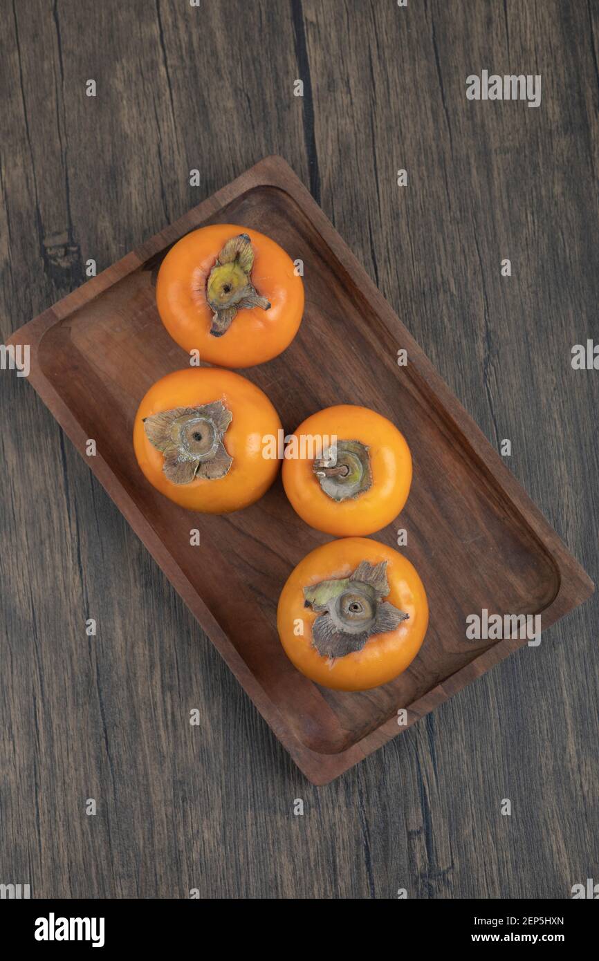 Teller mit leckeren fuyu-Kaki-Früchten auf Holzoberfläche Stockfoto