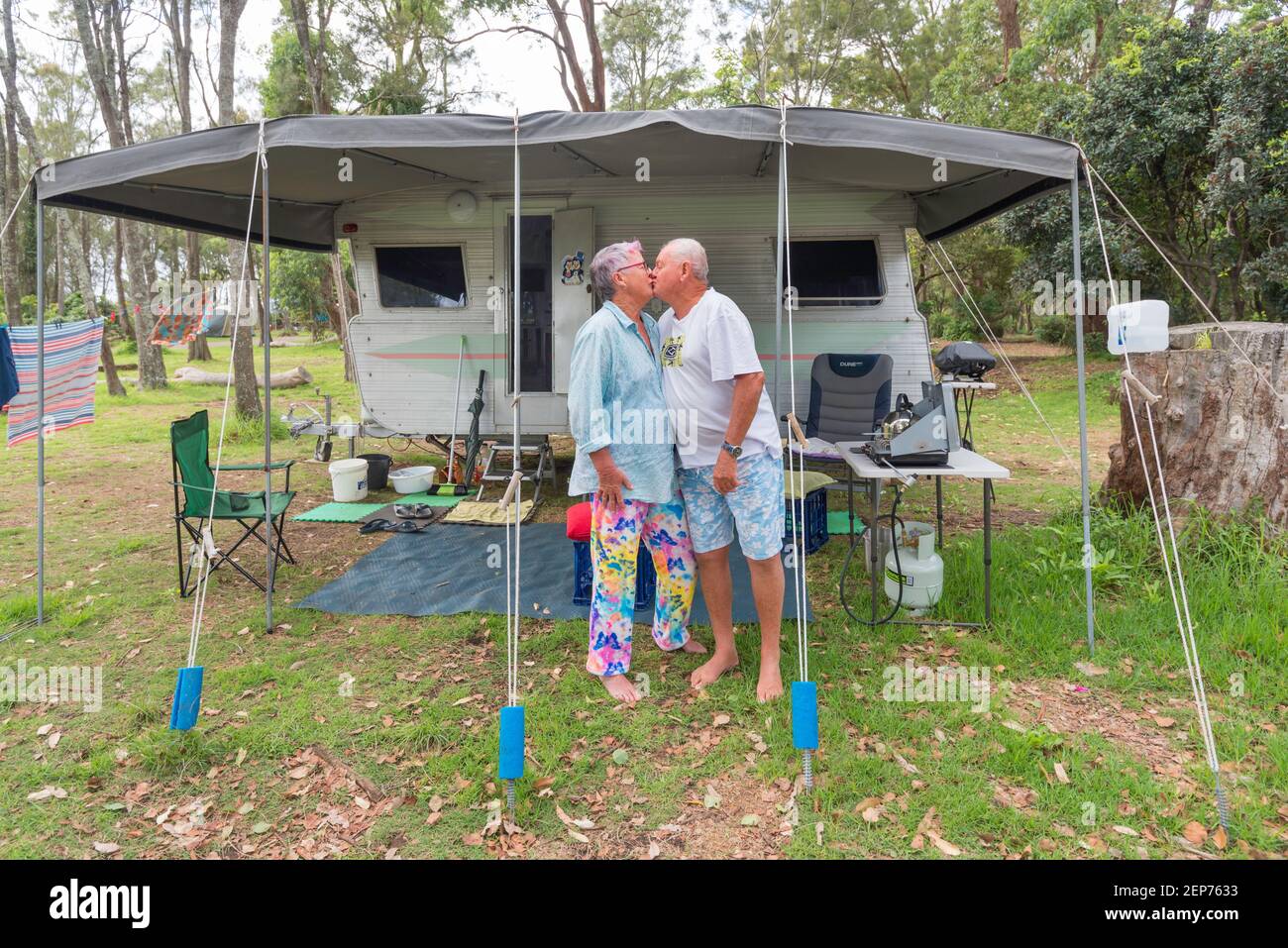 Graue Nomaden, Vicki und Gary (Middo) Middleton vor ihrem Wohnwagen und Markise auf einem Campingplatz in Bendelong, New South Wales, Australien Stockfoto