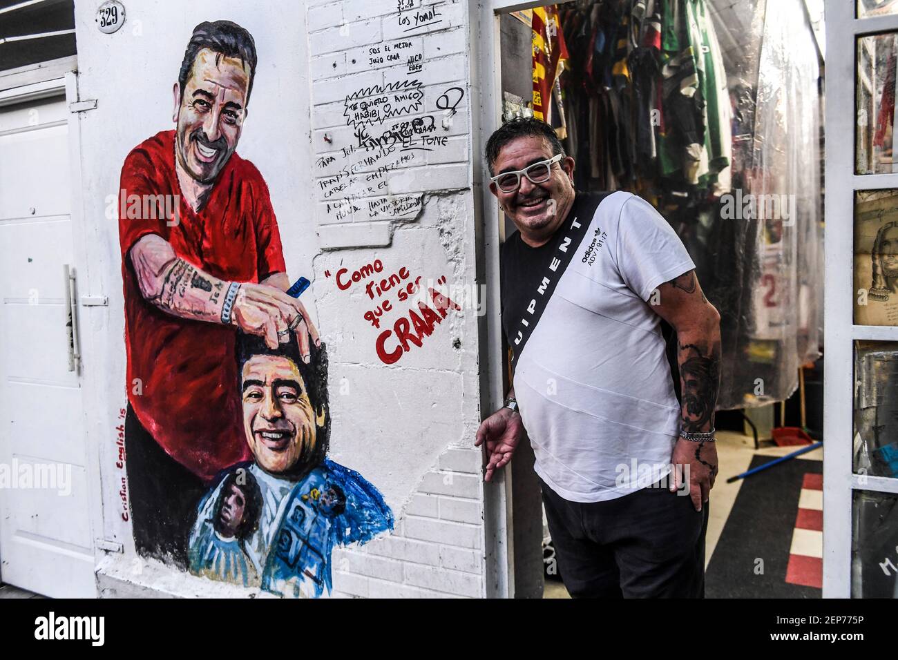 Buenos Aires, Argentinien. Februar 2021, 12th. Julio Pan steht neben einem Wandgemälde am Eingang seines Friseursalons, wo er zahlreiche Souvenirs zu Ehren des Fußballstars Maradona aufbewahrt und ausgestellt hat. (To dpa 'Maradonas Vermächtnis: Zwischen heiliger Anbetung und Schlammschlachten' von 27,02.2021) Credit: Fernando Gens/dpa/Alamy Live News Stockfoto