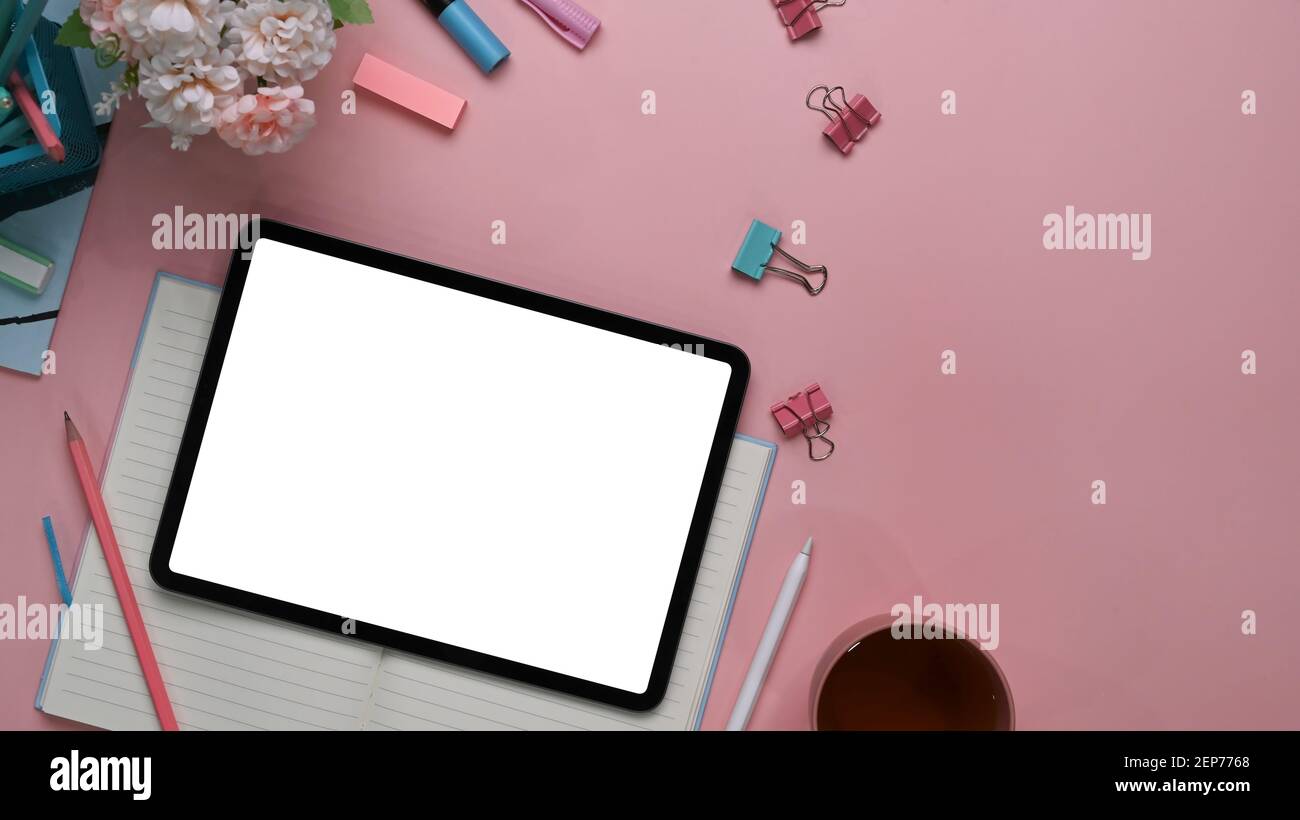 Ansicht des modernen femininen Arbeitsbereichs mit digitalem Tablet, Stylus Pen, Schreibwaren, Notizbuch und Kopierbereich auf rosa Hintergrund. Stockfoto