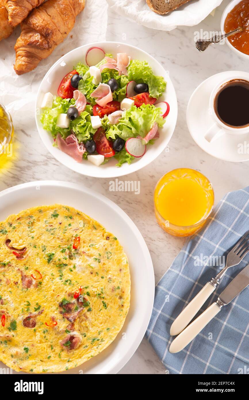 Eine große Auswahl an Speisen, darunter Omelette, Croissants, Salat, Brot, Kaffee und Orangensaft auf dem Tisch Stockfoto