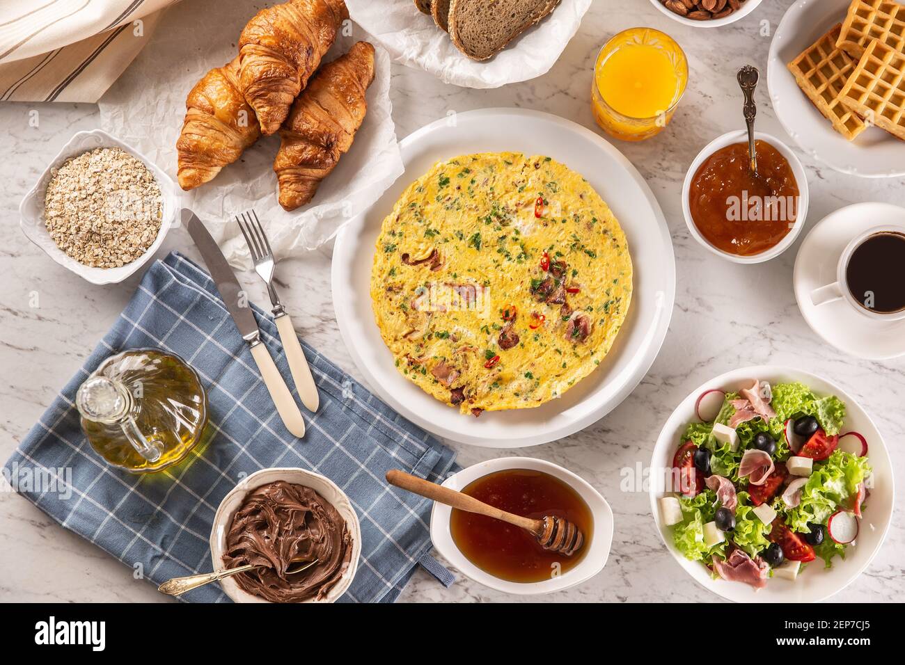 Große Auswahl an Speisen, darunter Omelette, Croissants, Salat, Brot, Haferflocken, Marmelade, Waffeln, Honig, Choclate-Aufstrich, Kaffee und Orangensaft serviert Stockfoto