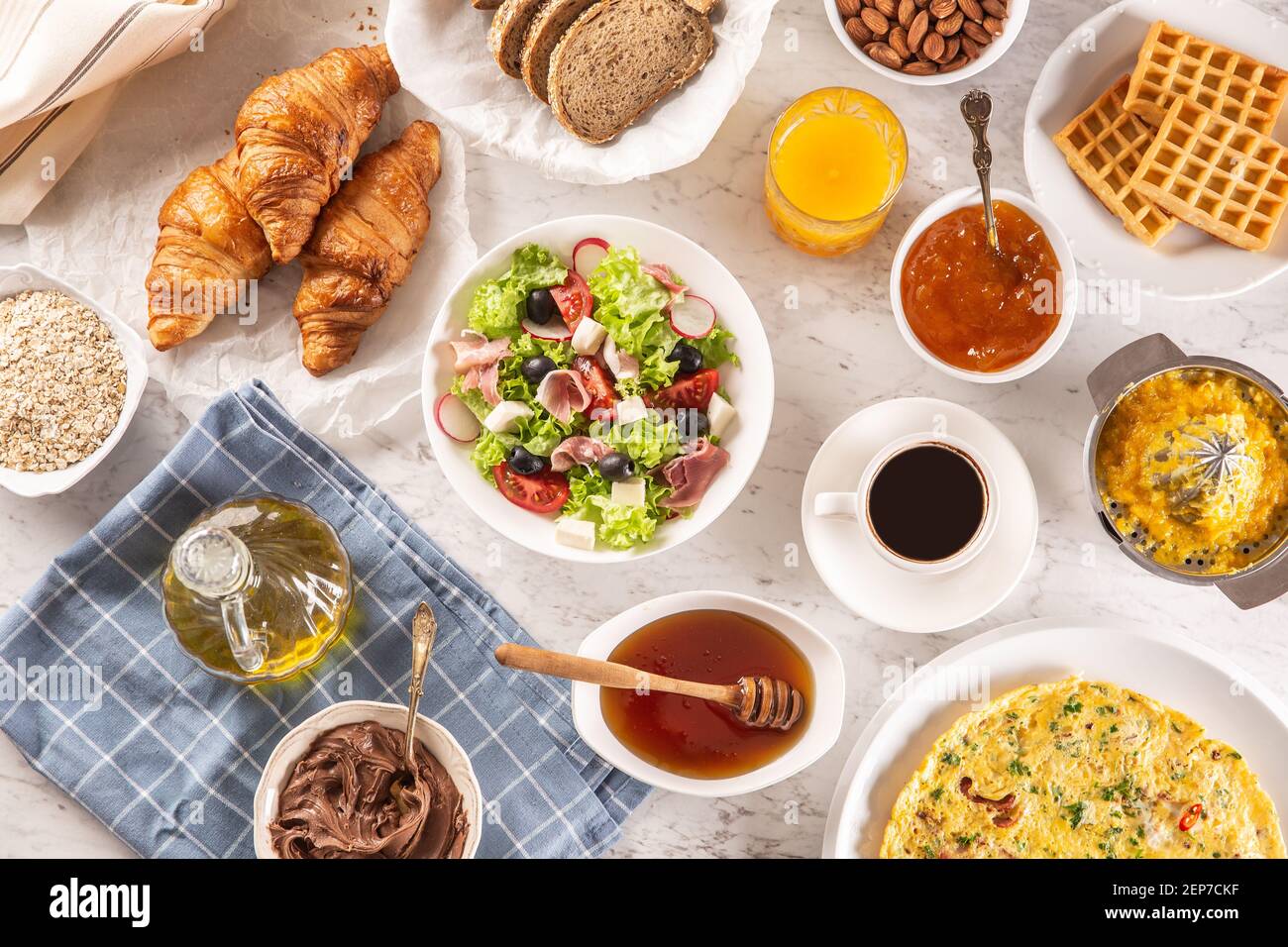 Große Auswahl an Speisen, darunter Omelette, Croissants, Salat, Brot, Haferflocken, Marmelade, Waffeln, Honig, Choclate-Aufstrich, Kaffee und Orangensaft serviert Stockfoto