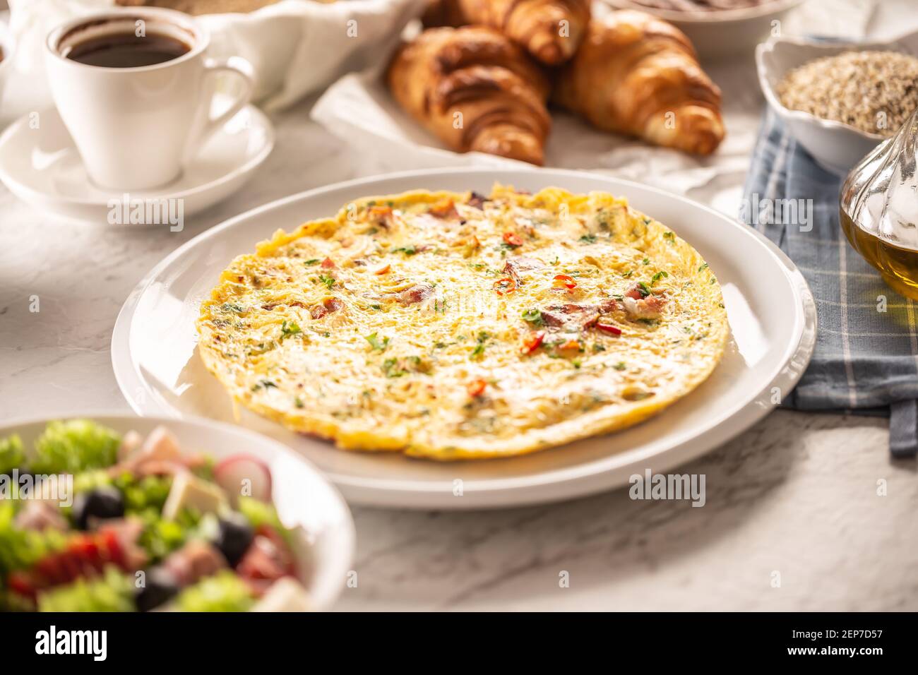 Frisches Omelett auf einem Teller mit gehacktem Chili und Koriander serviert, zusammen mit einer Auswahl an Frühstück und Kaffee Stockfoto