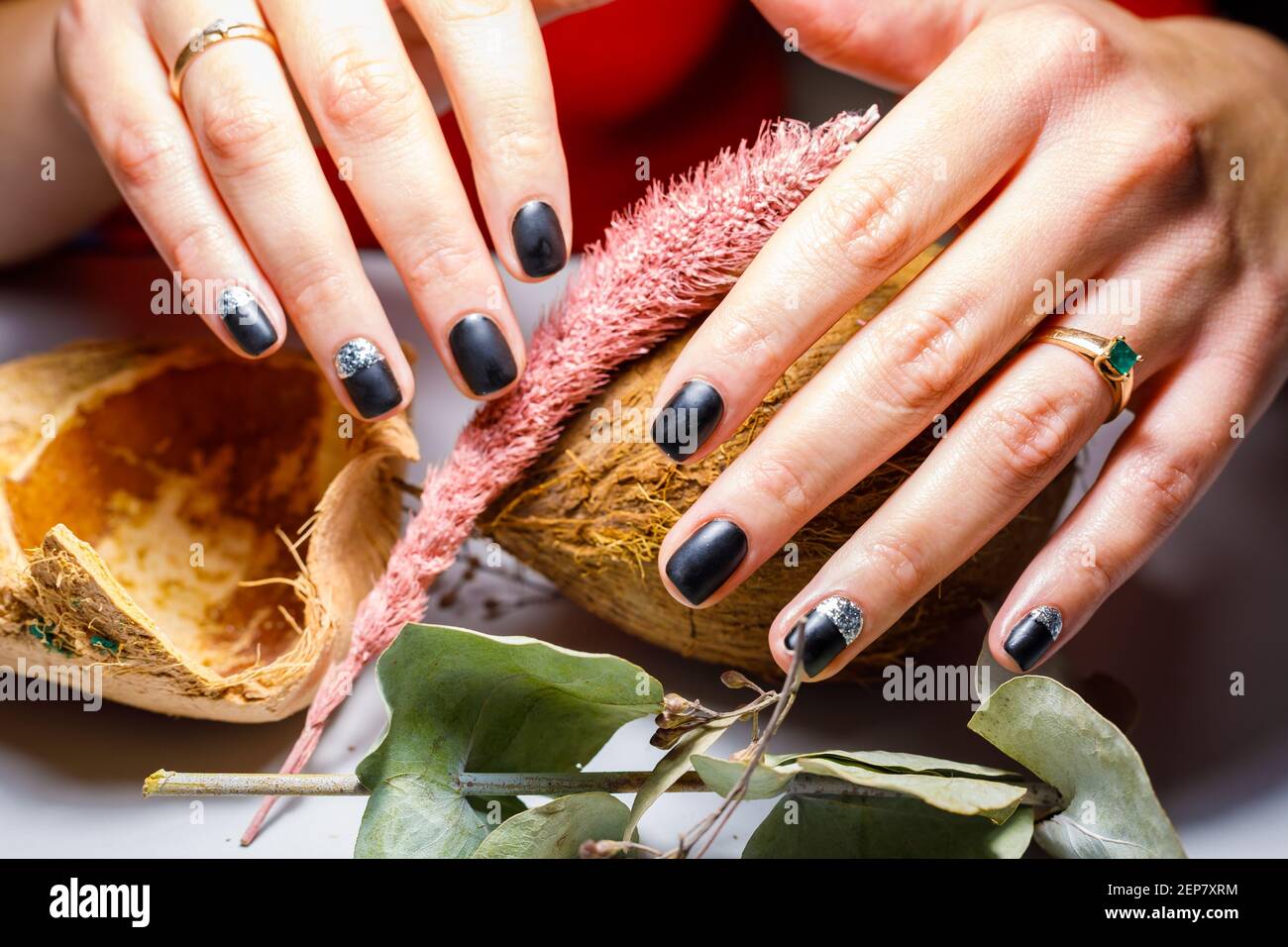 In einem Schönheitssalon macht der Meister eine Maniküre, trägt ein Muster auf den Nagel mit einem Pinsel, schwarzer Lack mit einem goldenen Muster. Stockfoto